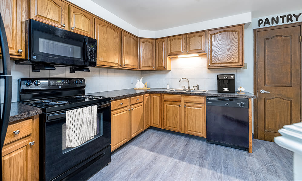 Large kitchen with oak cabinets and black appliances at Green Lake Apartments & Townhomes in Orchard Park, New York