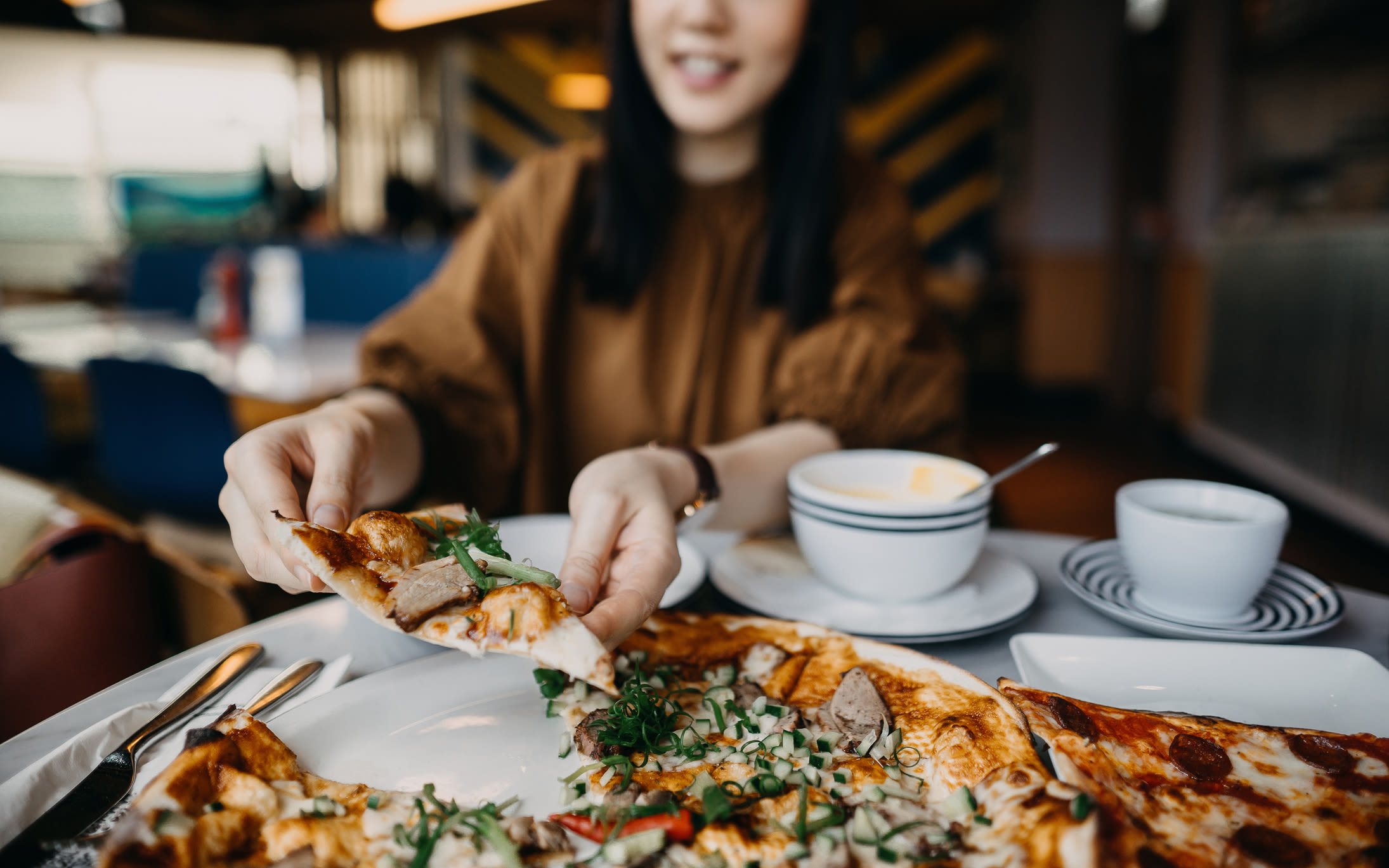 A woman eating pizza at restaurant near Mosby Bridge Street in Huntsville, Alabama