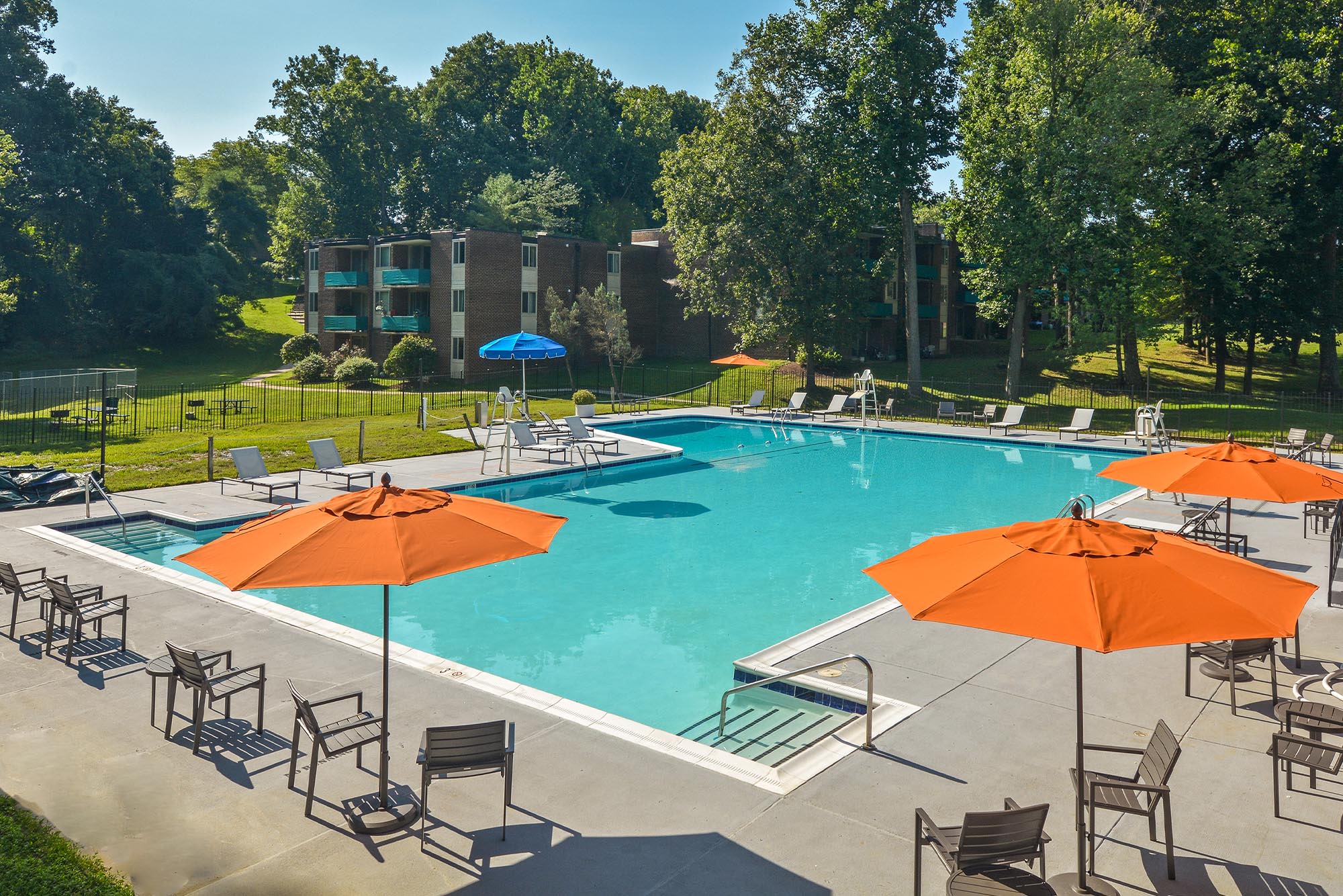 Swimming pool surrounded by patio seating and umbrellas at Landmark Glenmont Station in Silver Spring, Maryland