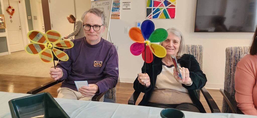 Elderly man and woman posing with their flower art crafts