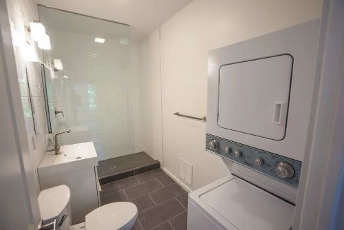 Tile floor bathroom with sliding glass door on the shower and washer dryer combo at Campus Prime in Syracuse, New York
