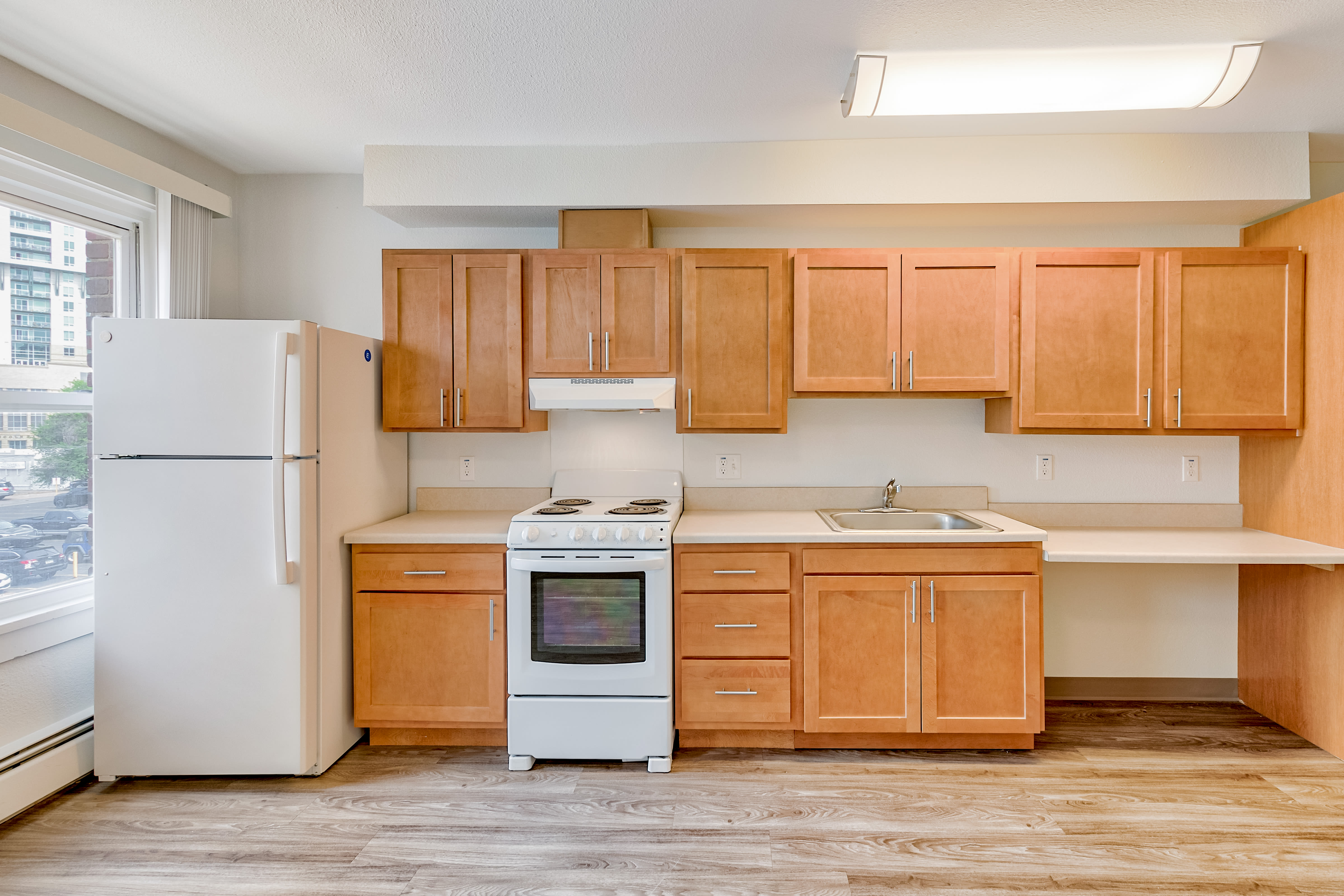 Fully equipped kitchen with natural wood cabinetry at Drehmoor Apartments in Denver, Colorado