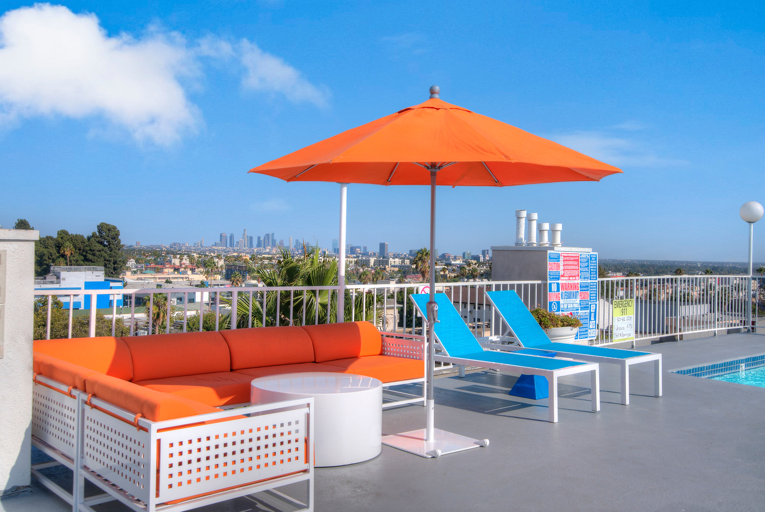 Poolside lounge chairs and an umbrella at The Jessica Apartments in Los Angeles, California
