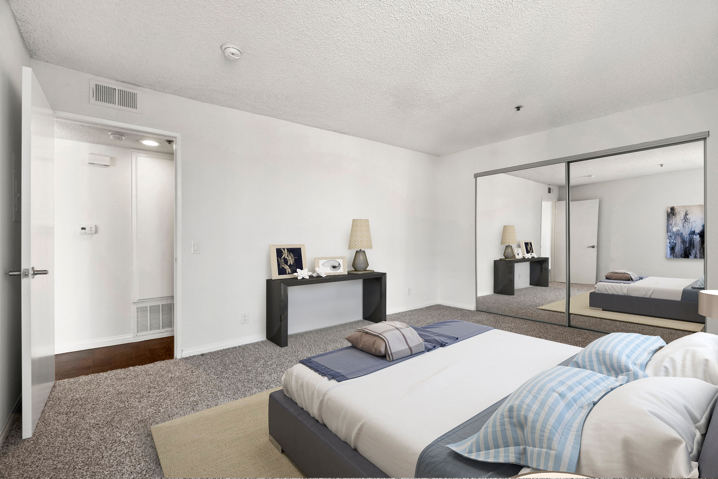 Model bedroom with sliding glass mirror closet at The Jessica Apartments in Los Angeles, California