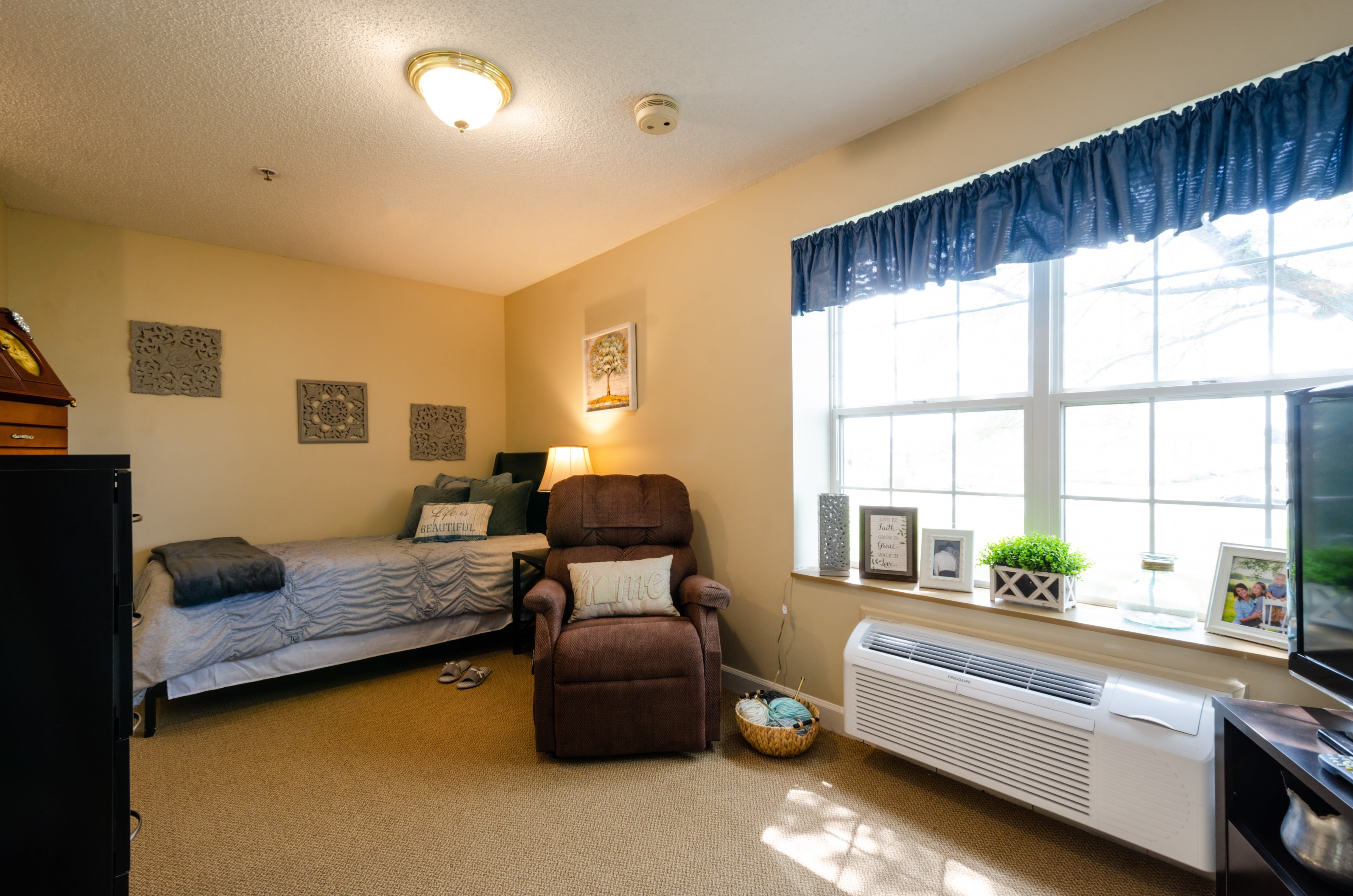 Furnished resident bedroom with large sunlit window at Trustwell Living at Miller Place in Celina, Ohio