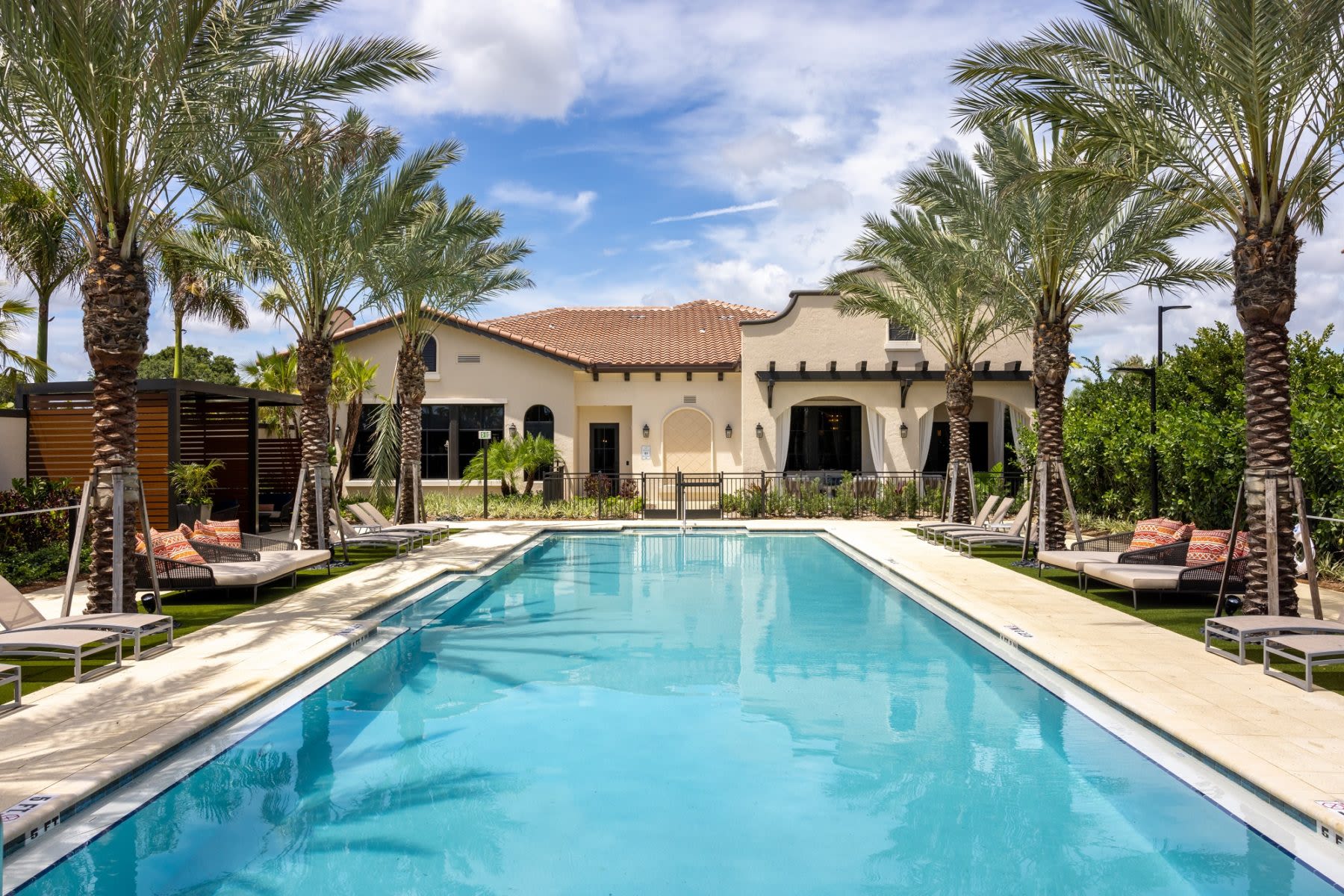 Pool oasis with palm trees, lounge chairs, clubhouse at Locklyn West Palm, West Palm Beach, Florida
