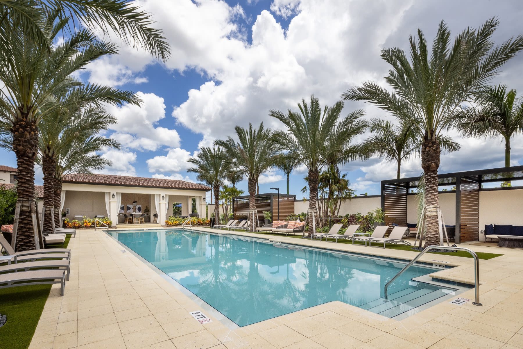 Serene pool with palm trees, loungers, clubhouse at Locklyn West Palm, West Palm Beach, Florida