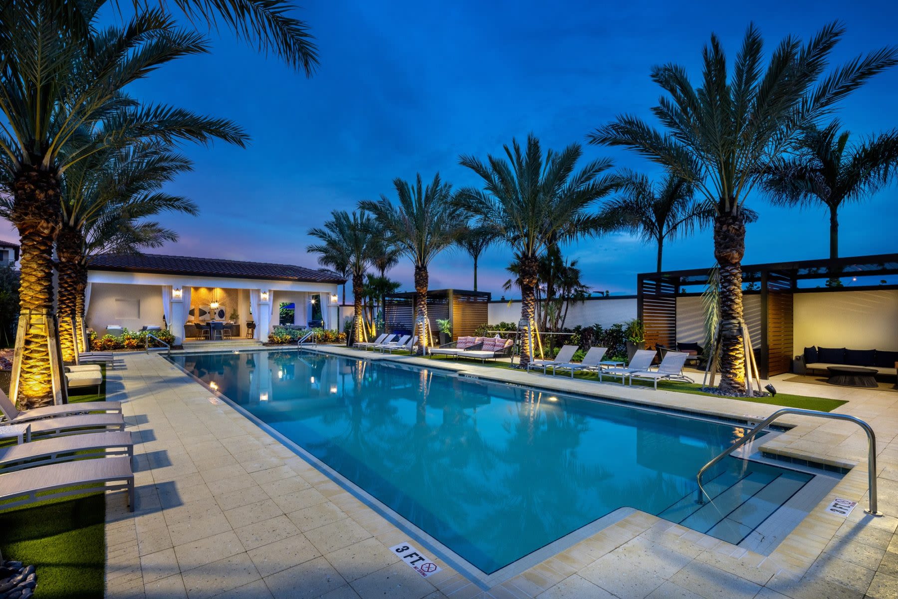 Palm-fringed poolside with loungers, clubhouse at Locklyn West Palm, West Palm Beach, Florida