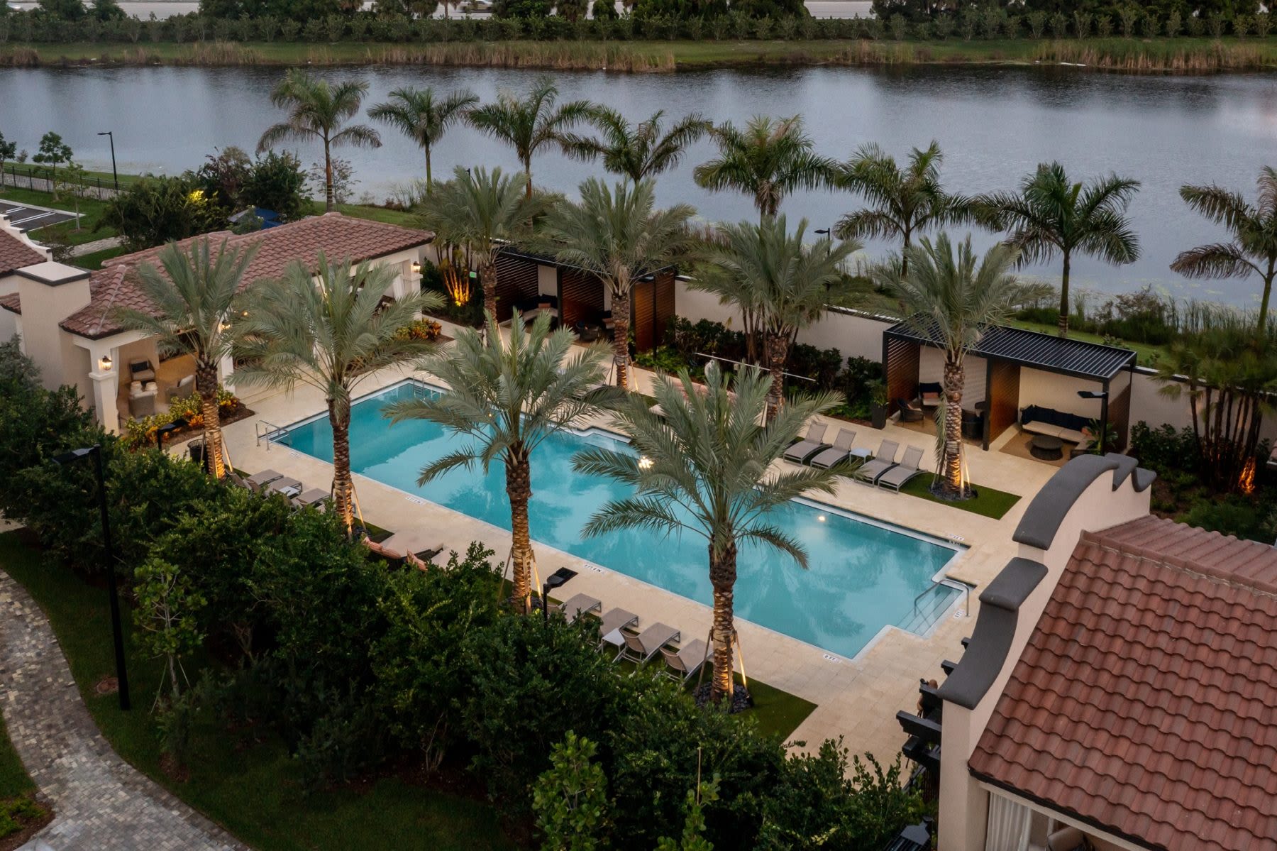 Resort-style pool with palm trees, loungers, clubhouse at Locklyn West Palm, West Palm Beach, Florida
