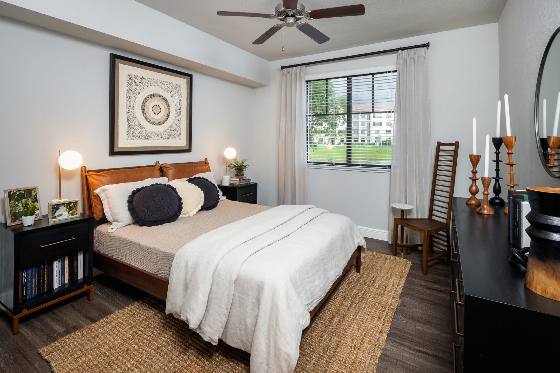 A furnished apartment model bedroom with natural light, modern furnishings, and wood-style flooring at Locklyn West Palm in West Palm Beach, Florida