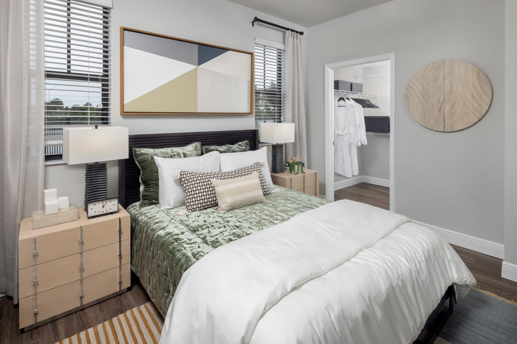 At Locklyn West Palm in West Palm Beach, Florida, a furnished apartment model bedroom features natural light, modern furnishings, and stylish wood-style flooring