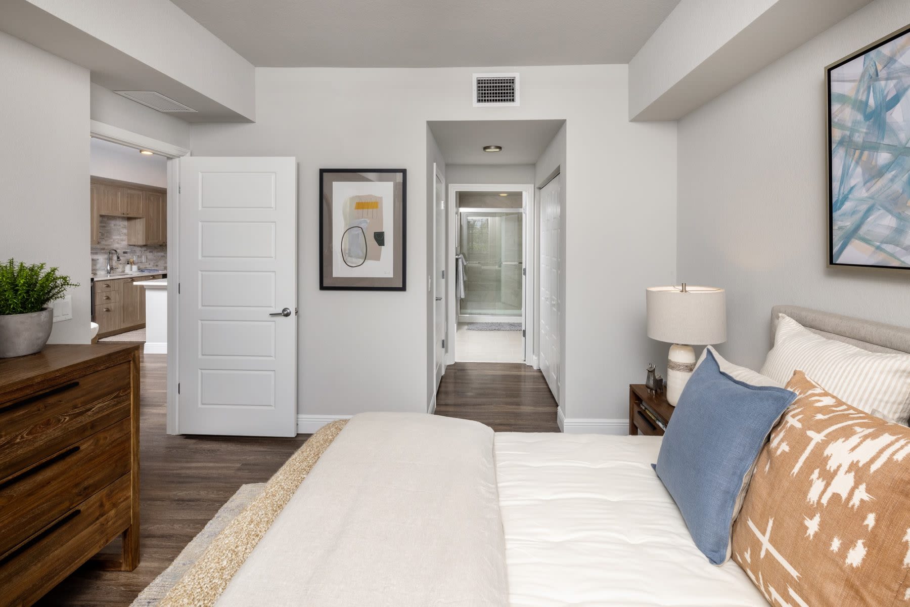 Immerse yourself in the serenity of a furnished apartment model bedroom featuring natural light, contemporary furnishings, and the warmth of wood-style flooring at Locklyn West Palm in West Palm Beach, Florida