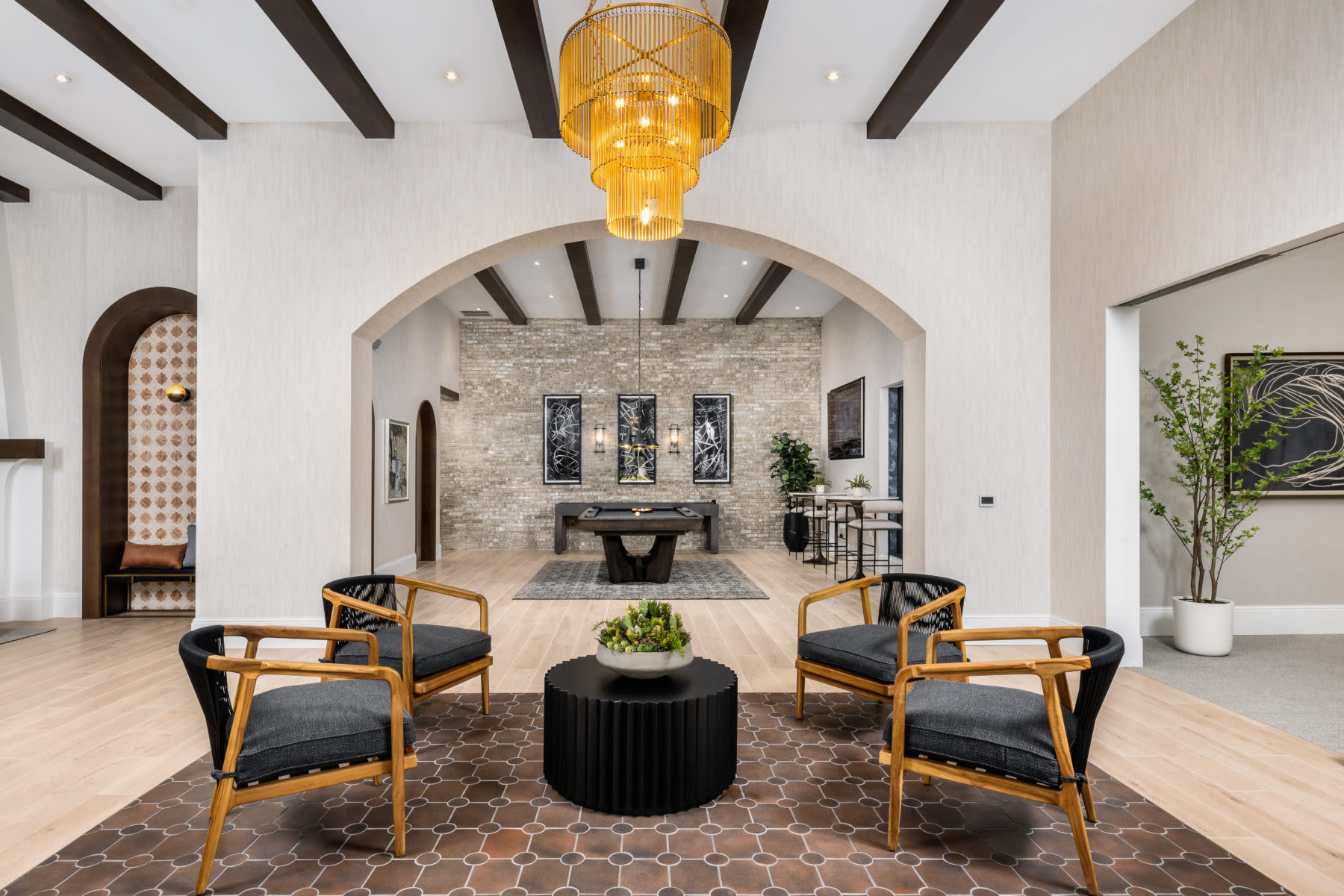 Experience the inviting atmosphere of a furnished clubhouse adorned with natural light, modern furnishings, and stylish wood-style flooring at Locklyn West Palm in West Palm Beach, Florida
