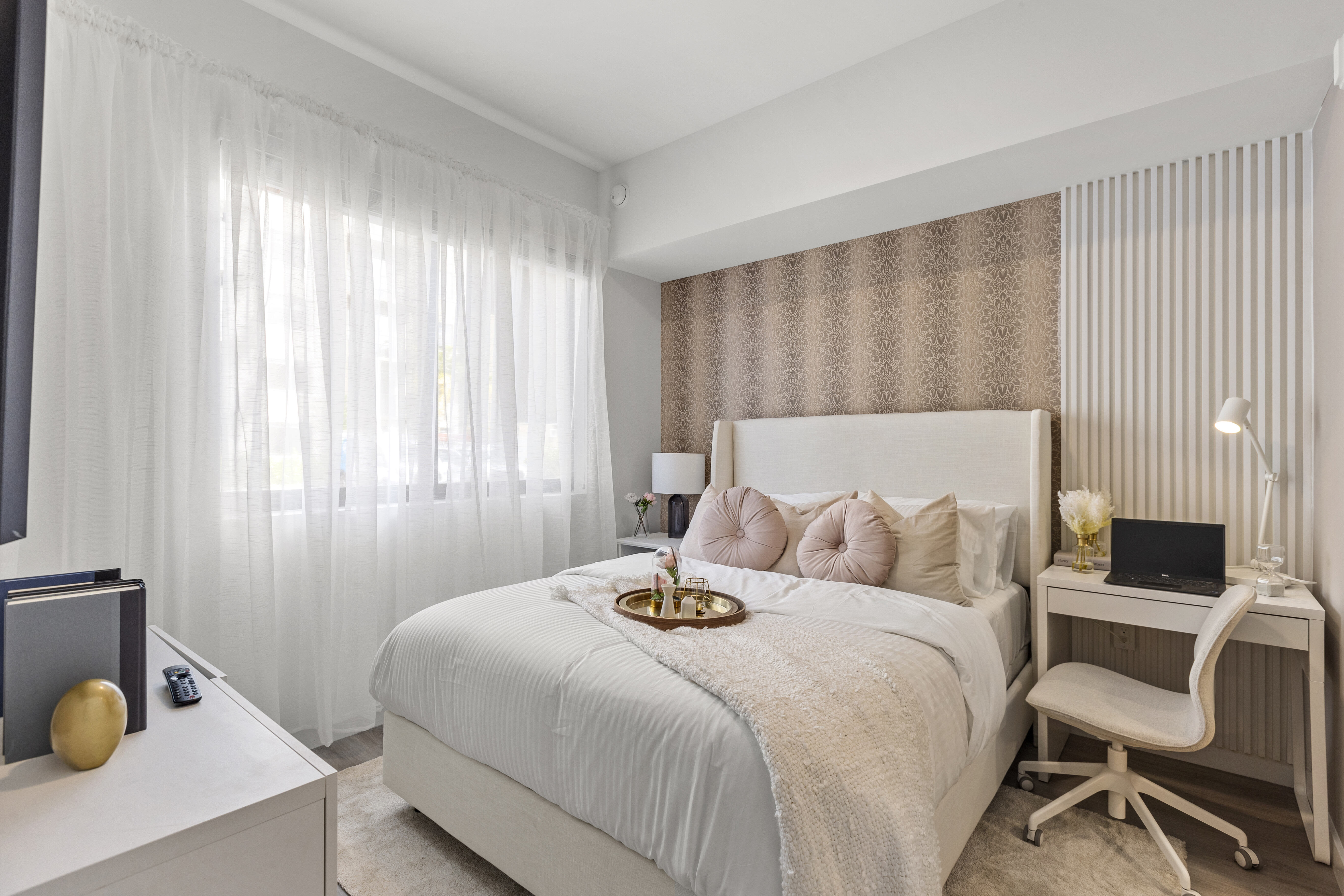 Modern furnishings, natural light, and wood-style flooring create an inviting atmosphere in a furnished apartment model bedroom at Pine Ridge in West Palm Beach, Florida