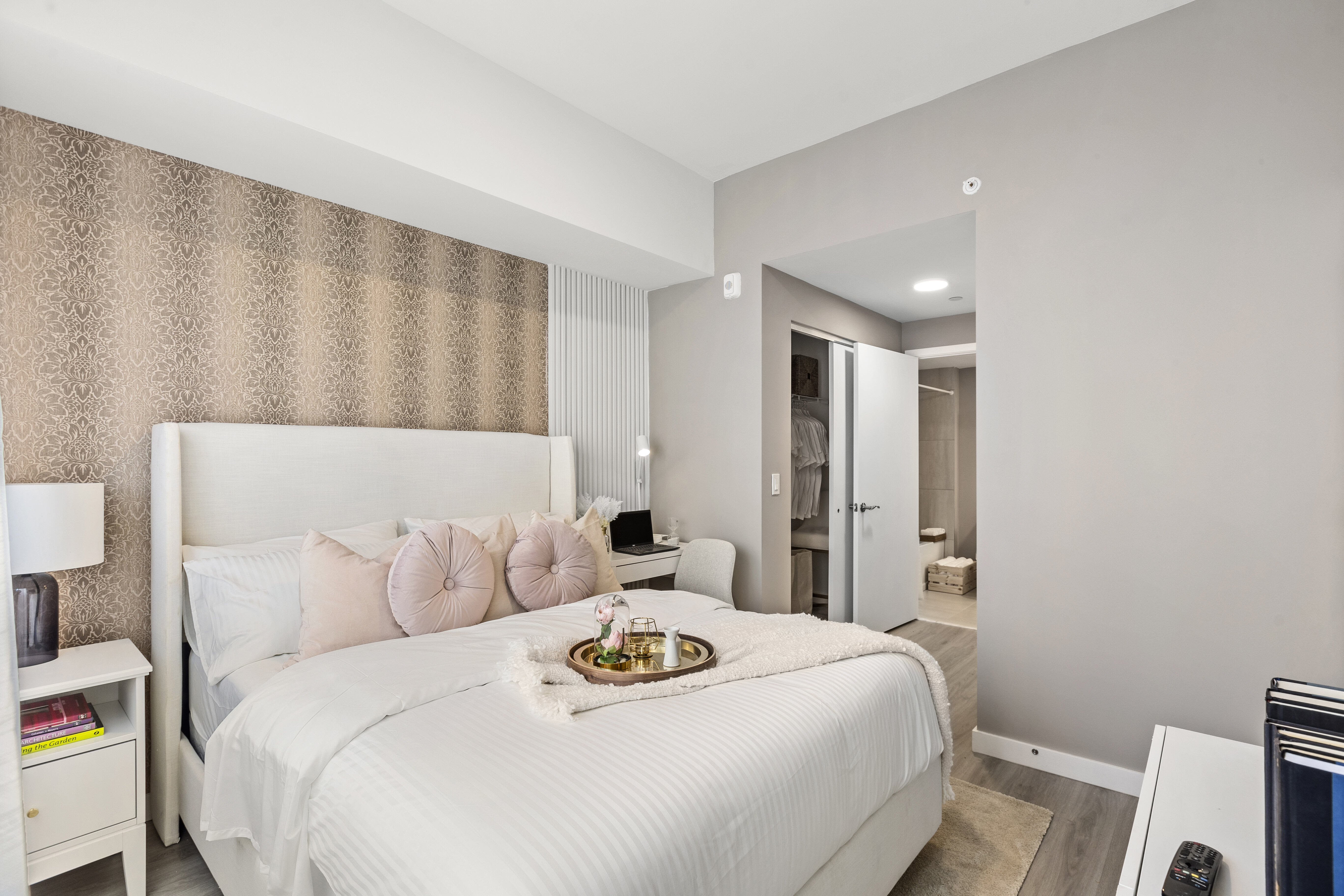 Step into a furnished apartment model bedroom at Pine Ridge in West Palm Beach, Florida, featuring natural light, contemporary furnishings, and wood-style flooring