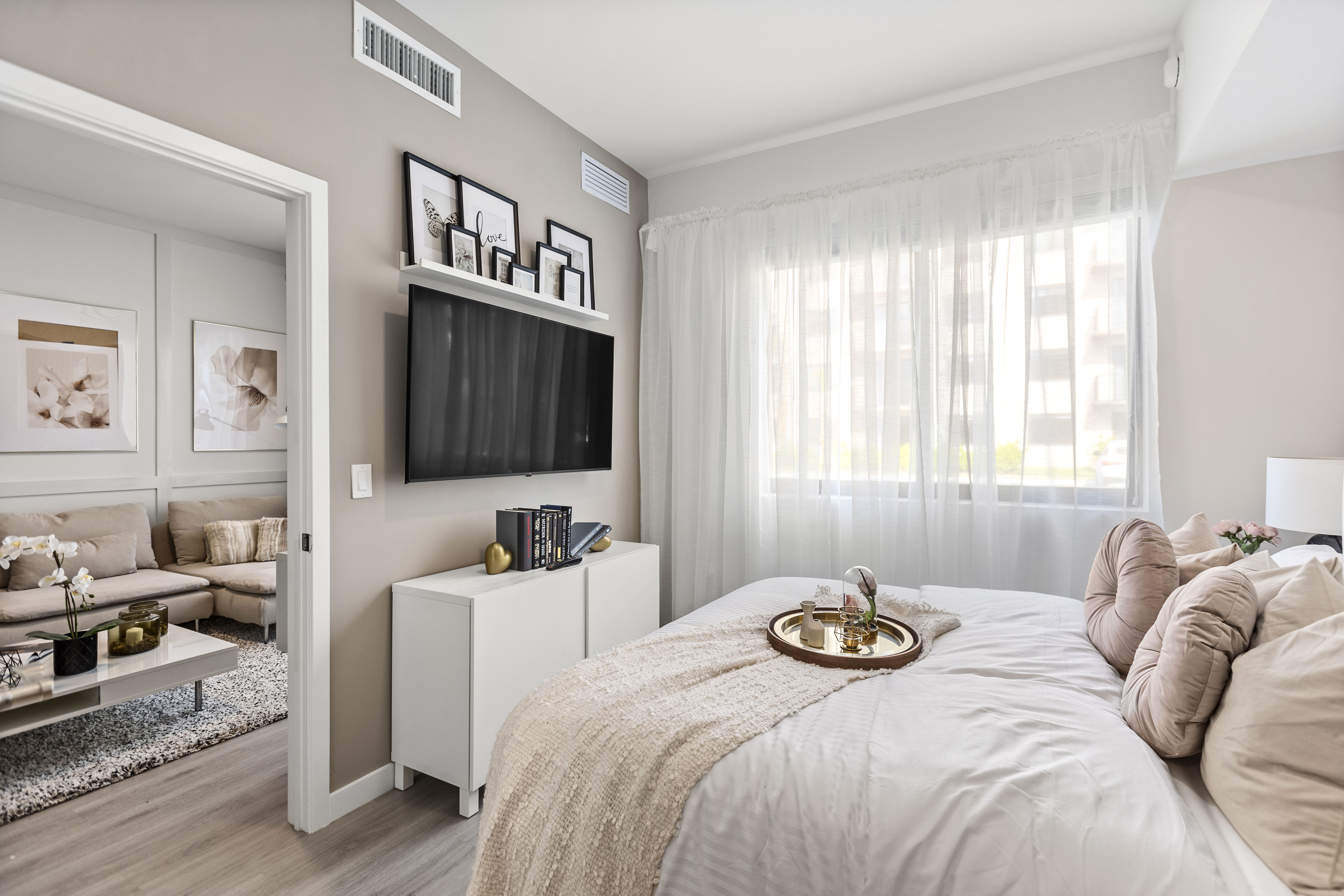 At Pine Ridge in West Palm Beach, Florida, a furnished apartment model bedroom features natural light, modern furnishings, and stylish wood-style flooring