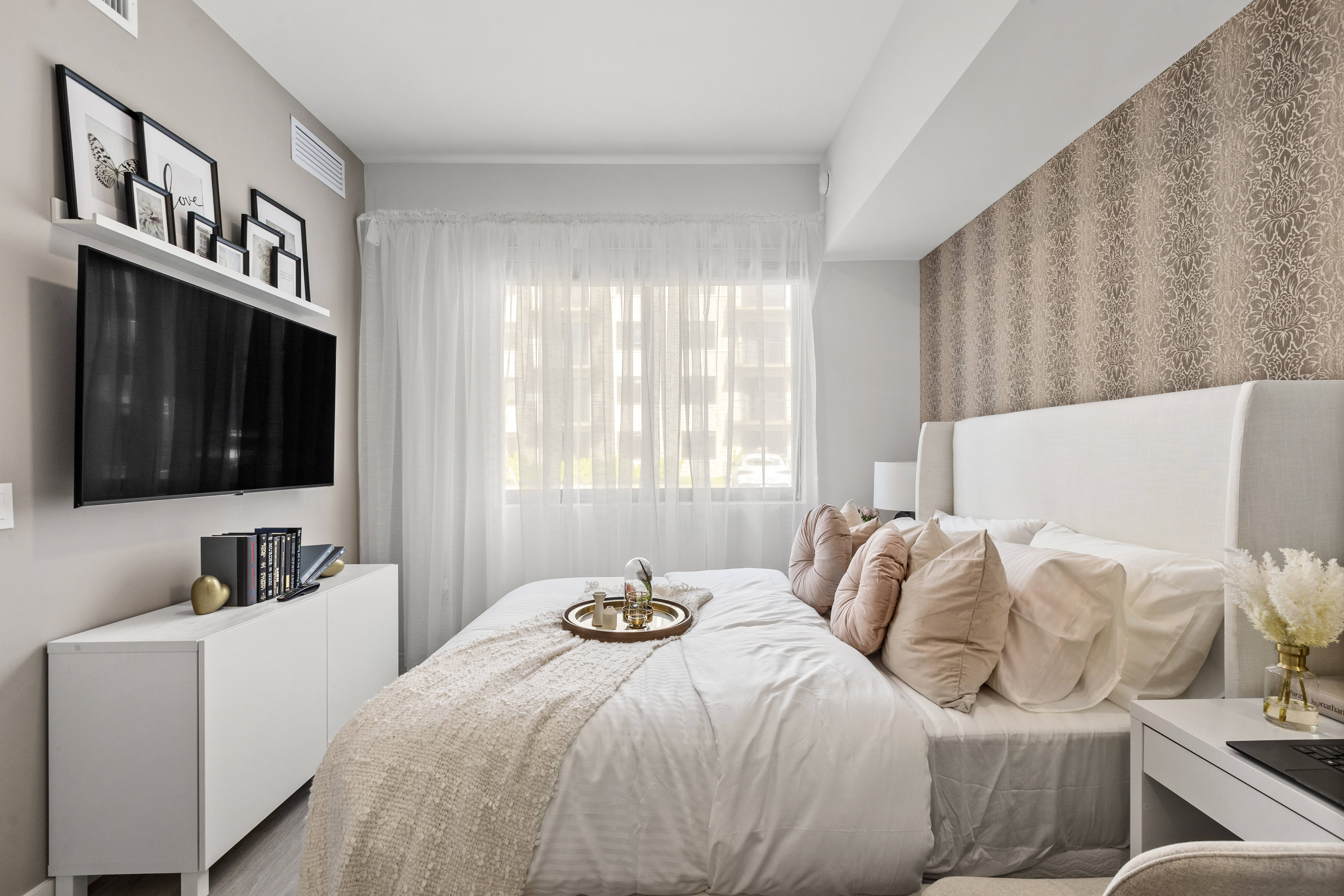Experience the appeal of a furnished apartment model bedroom with natural light, modern furnishings, and wood-style flooring at Pine Ridge in West Palm Beach, Florida