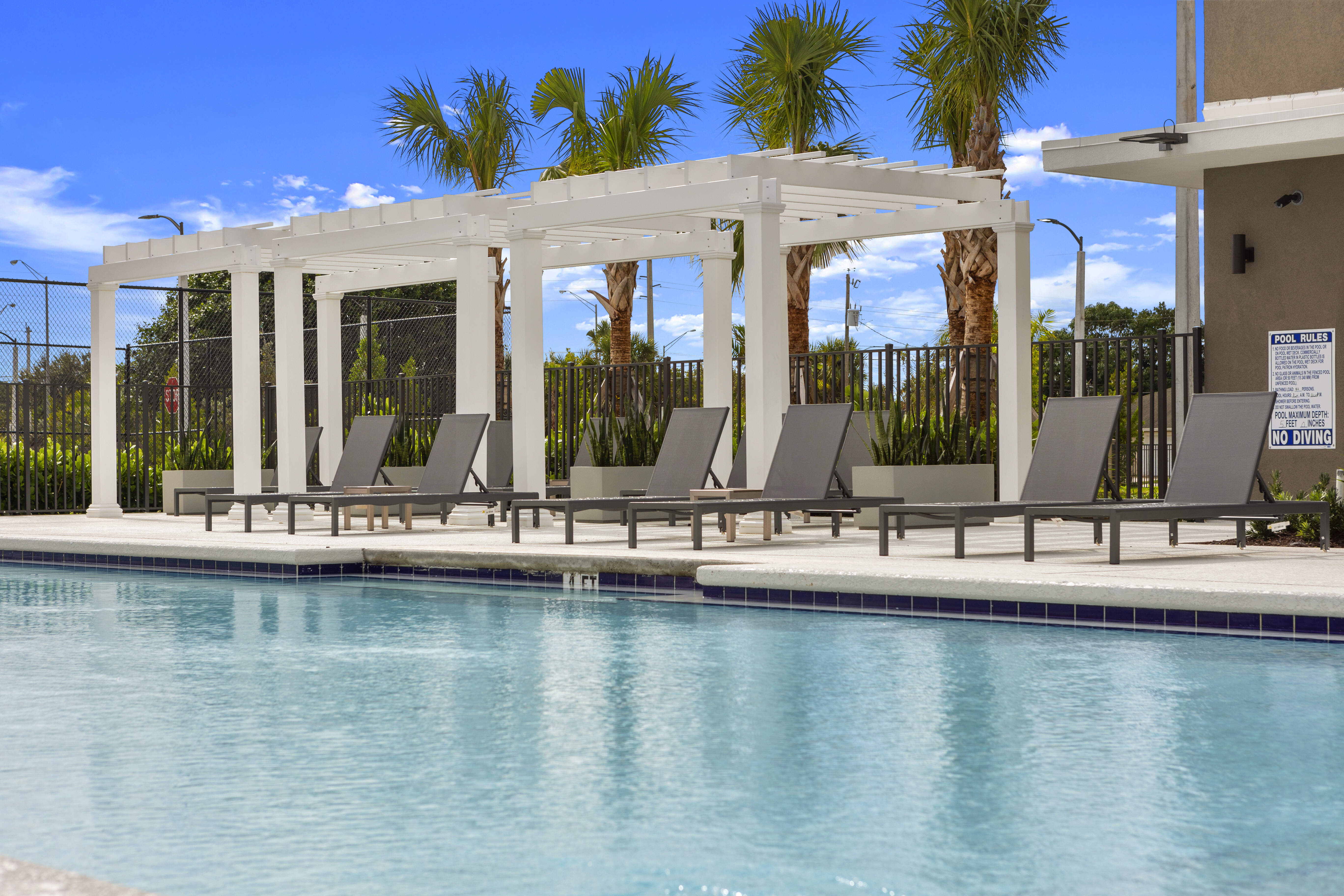High-end swimming pool with lounge chairs and palm trees at Pine Ridge in West Palm Beach, Florida