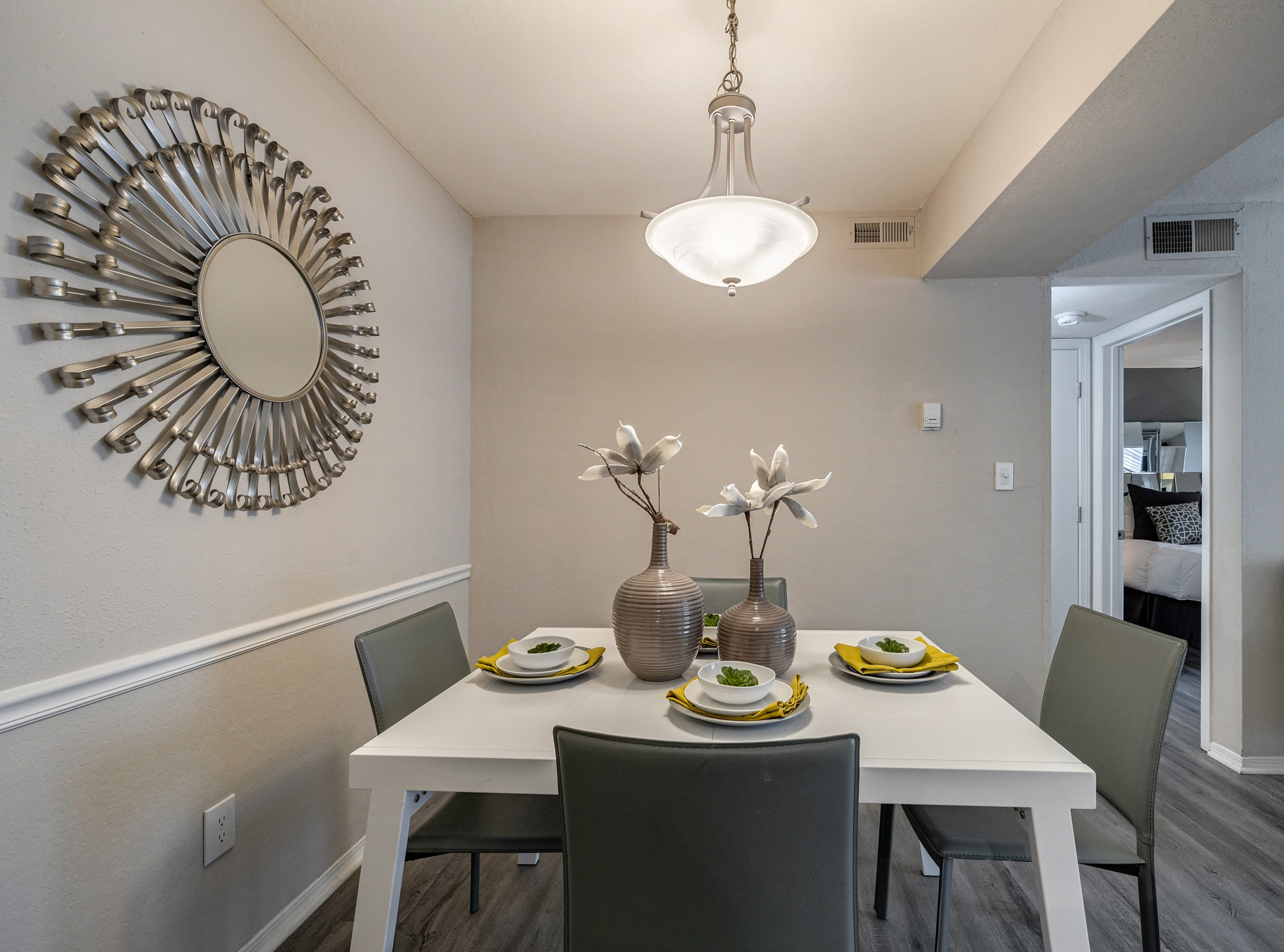 Dining area and kitchen with hardwood-style flooring and a warm yellow accent wall in a model home at Castlegate Collier Hills in Atlanta, Georgia