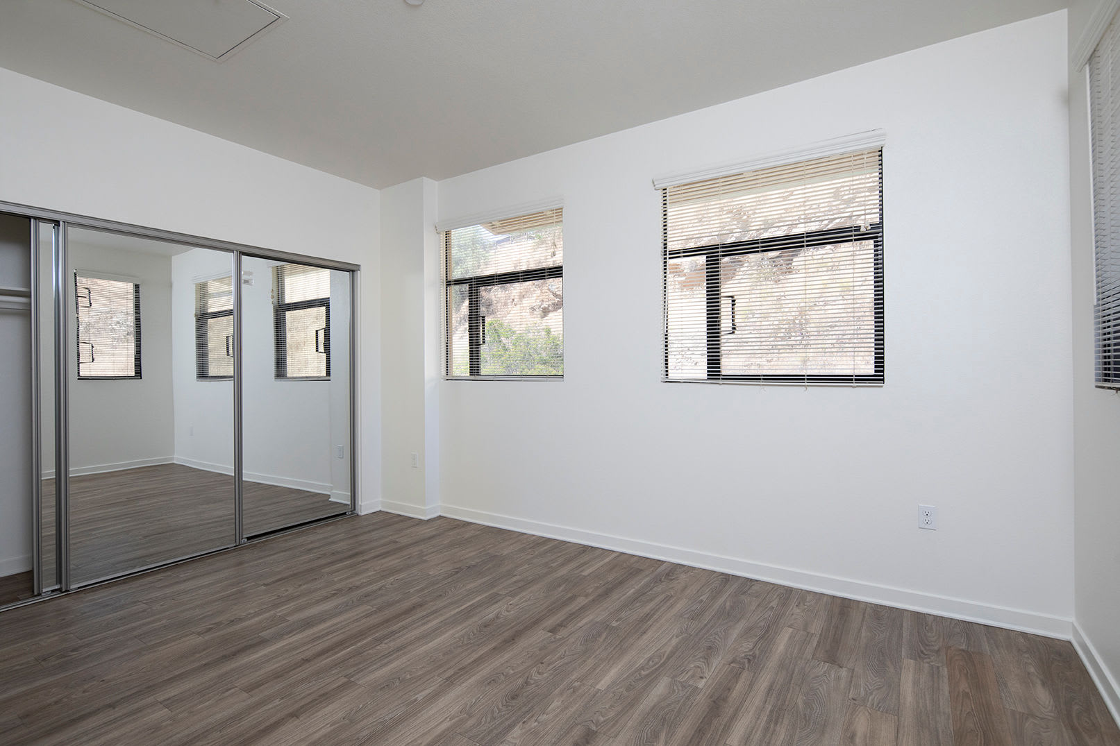 Model bedroom with mirrored closets at The Quarry Apartments in La Mesa, California