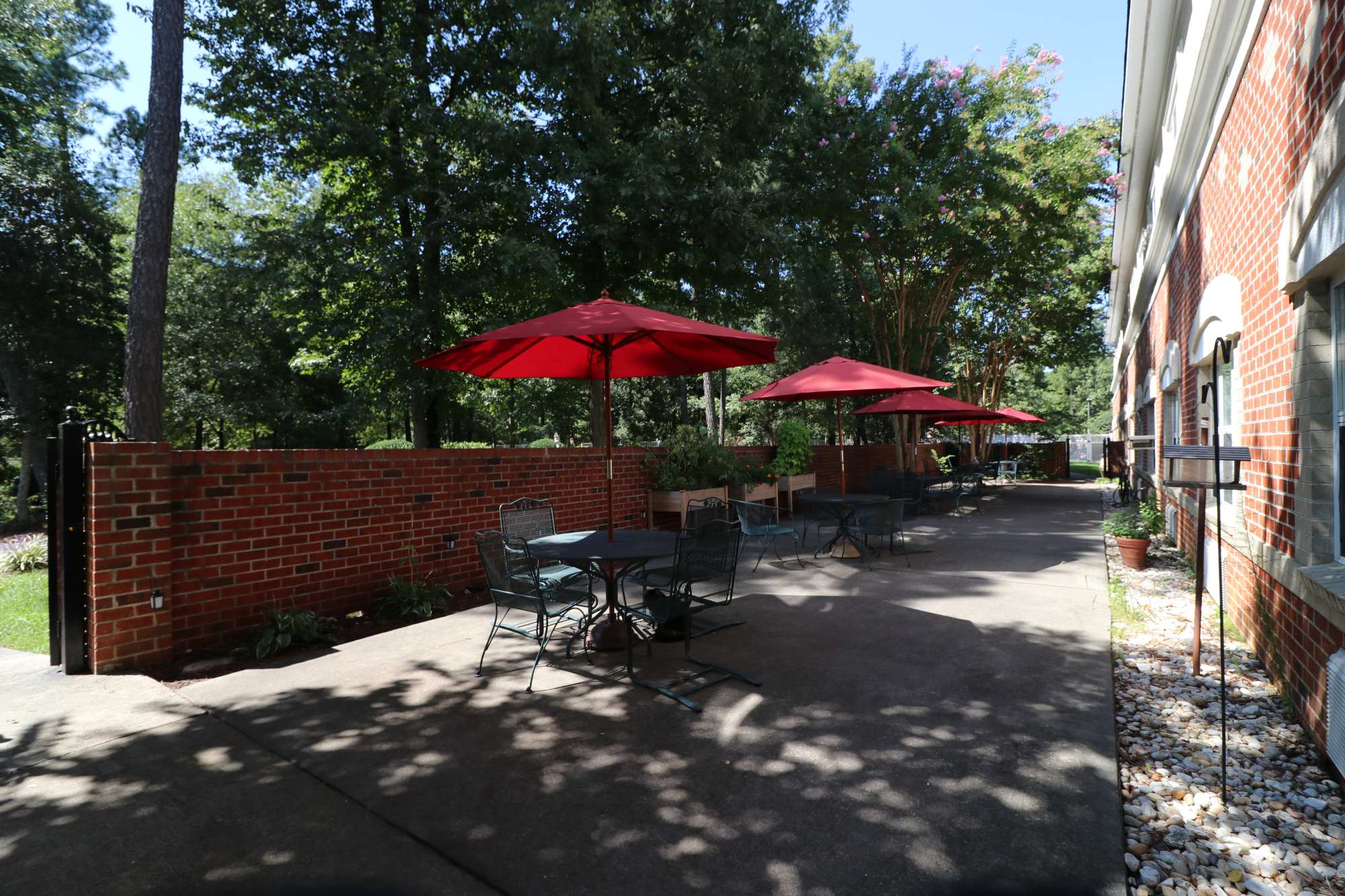 Outdoor patio area with several red umbrellas providing shade to tables and chairs at The Crossings at Ironbridge in Chester, Virginia