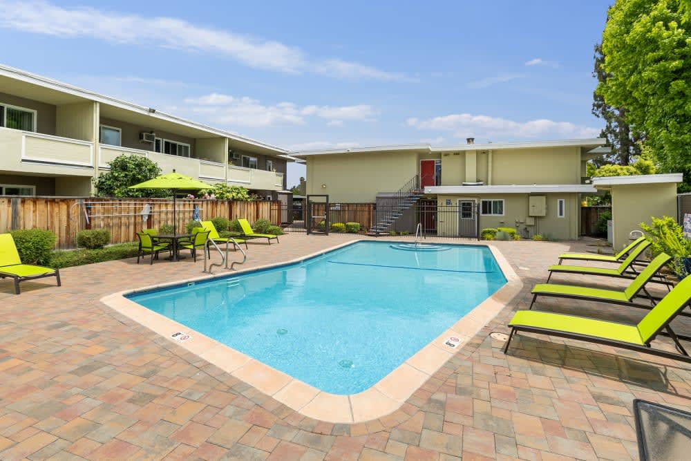 Swimming pool and vibrant green lounge chairs at Parkway Apartments in Fremont, California