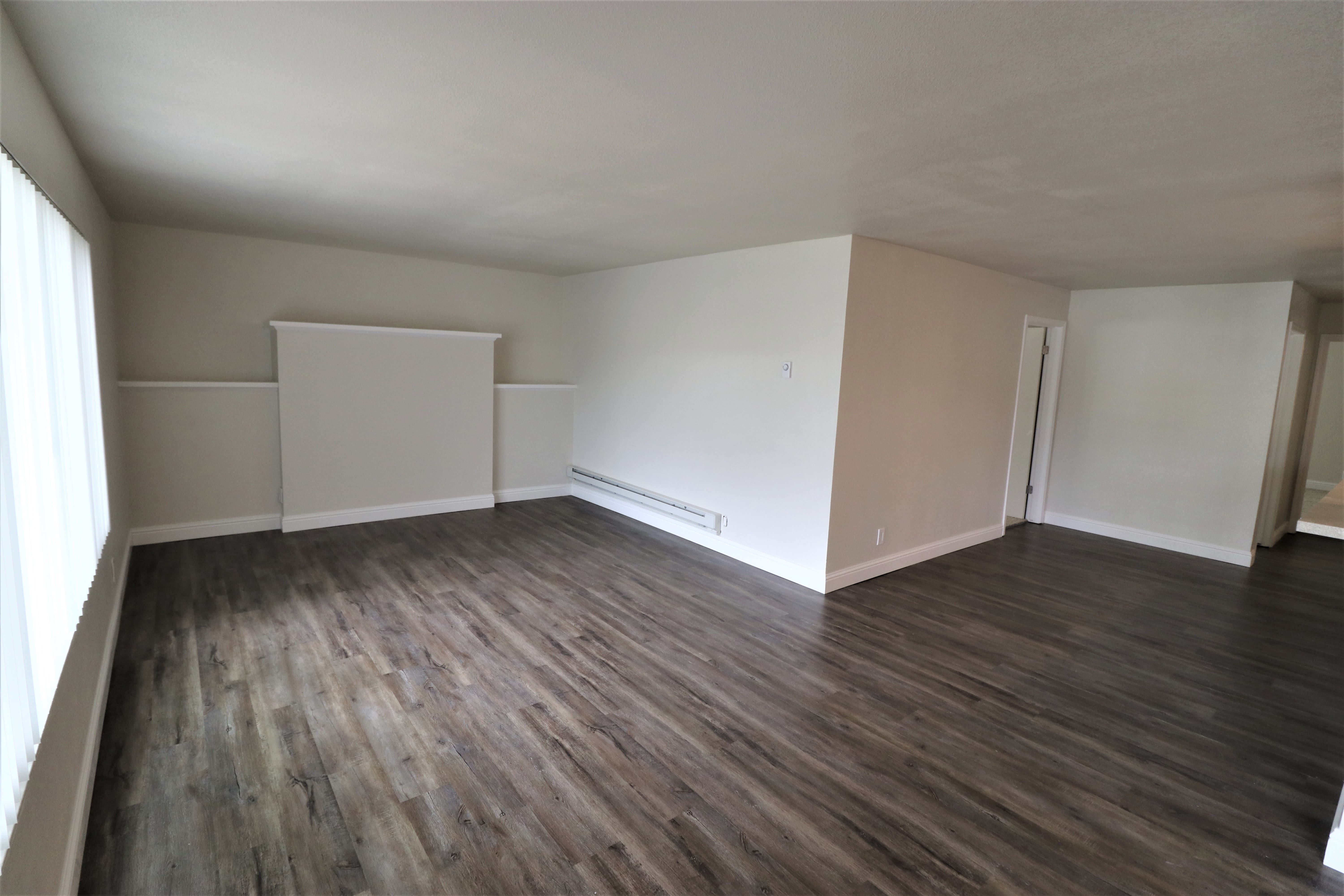 Large living room with lots of space and wood-style flooring at Marina Haven Apartments in San Leandro, California
