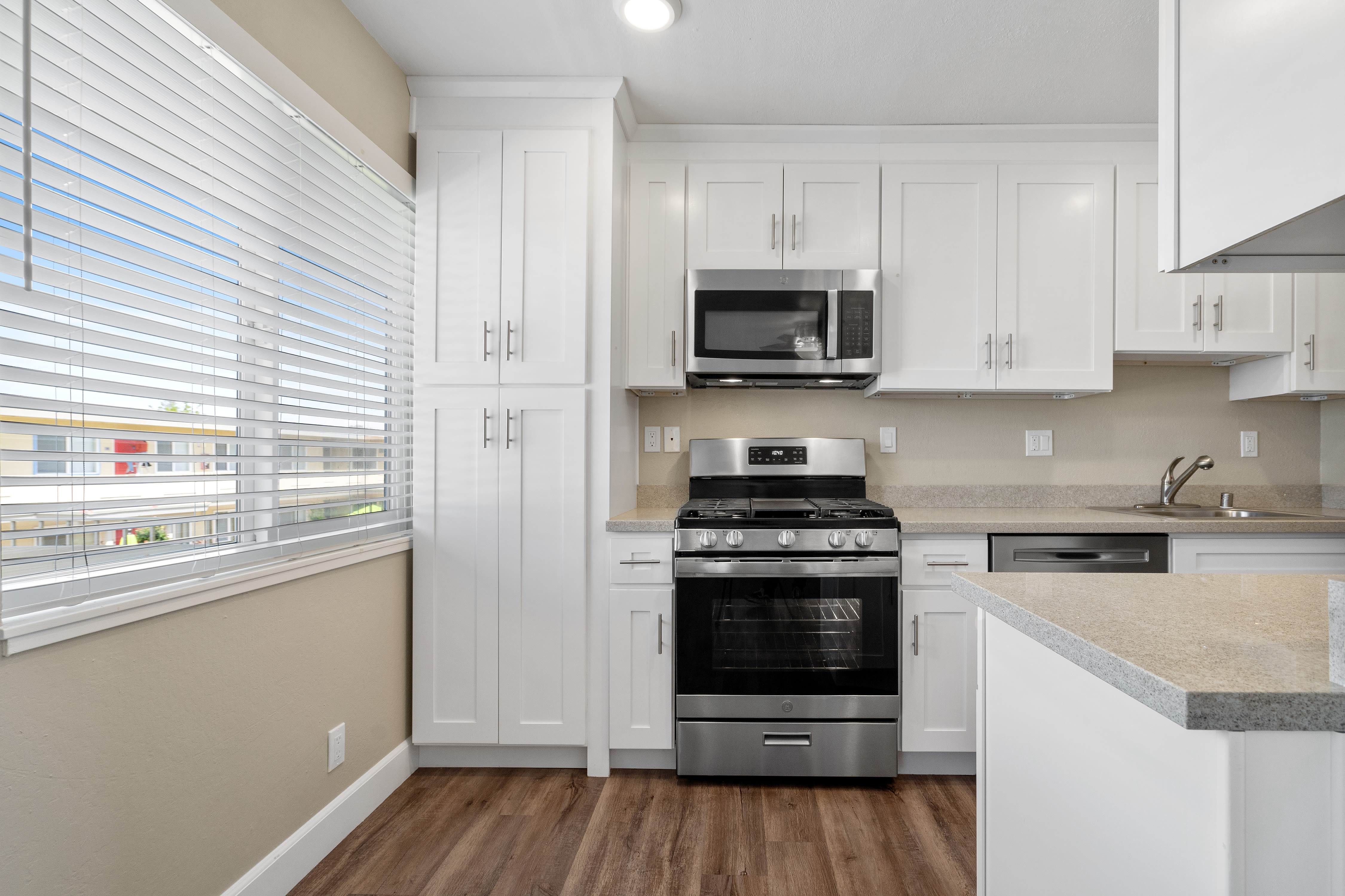 Kitchen with wood-style flooring, microwave, and stove at Bon Aire Apartments in Castro Valley, California