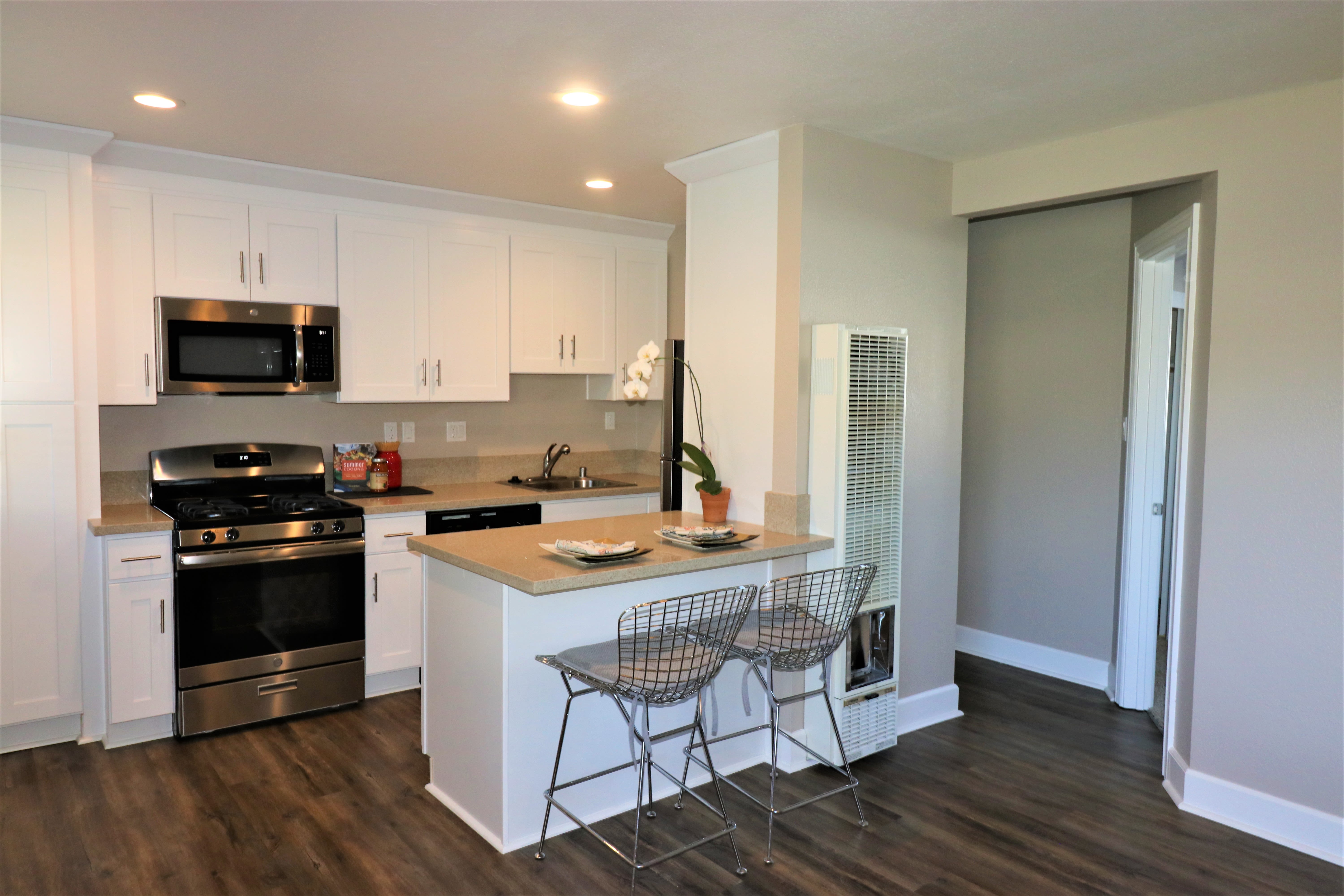 Kitchen with shiny stainless-steel appliances and breakfast counter at Bon Aire Apartments in Castro Valley, California