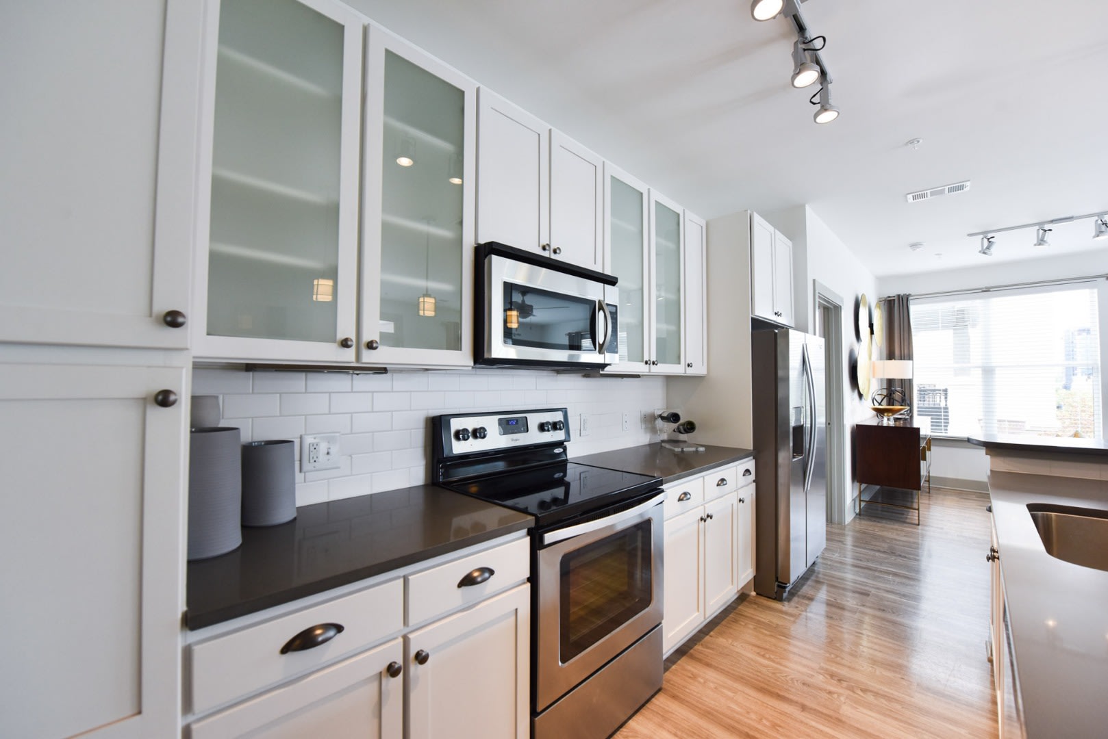 Apartments Near Westside Park -The Haven at Avalon - Spacious Kitchen with White Cabinets, Granite or Quartz Countertops, Tile Backsplash, Wood Grain Plank Flooring, and Stainless Steel Appliances.