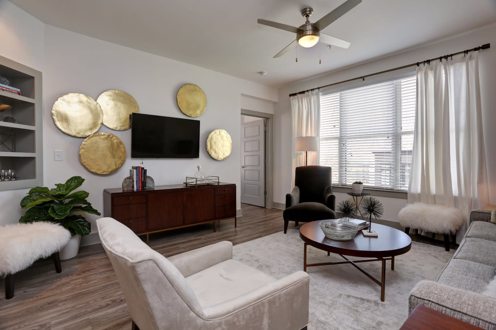 Apartments Near The Cottage -The Haven at Avalon - Spacious Furnished Living Room with Wood Grain Plank Flooring, a Ceiling Fan, and a Wide Window.