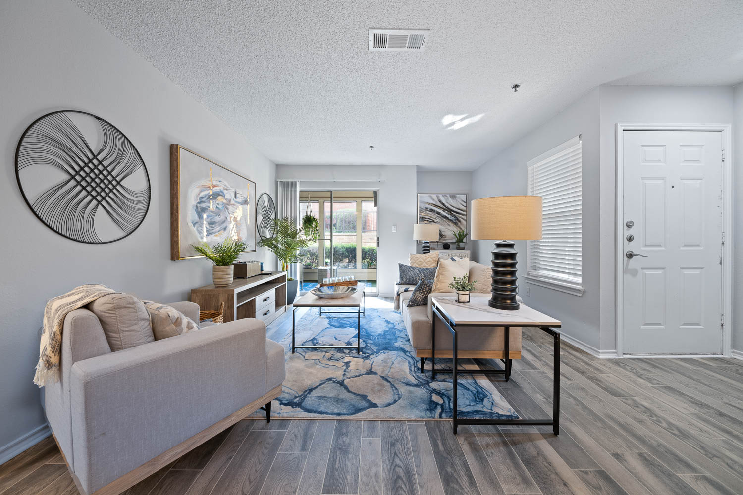 Living room, dining area, and kitchen of a beautiful open layout model apartment with wood-style flooring at Somerset in Lewisville, Texas