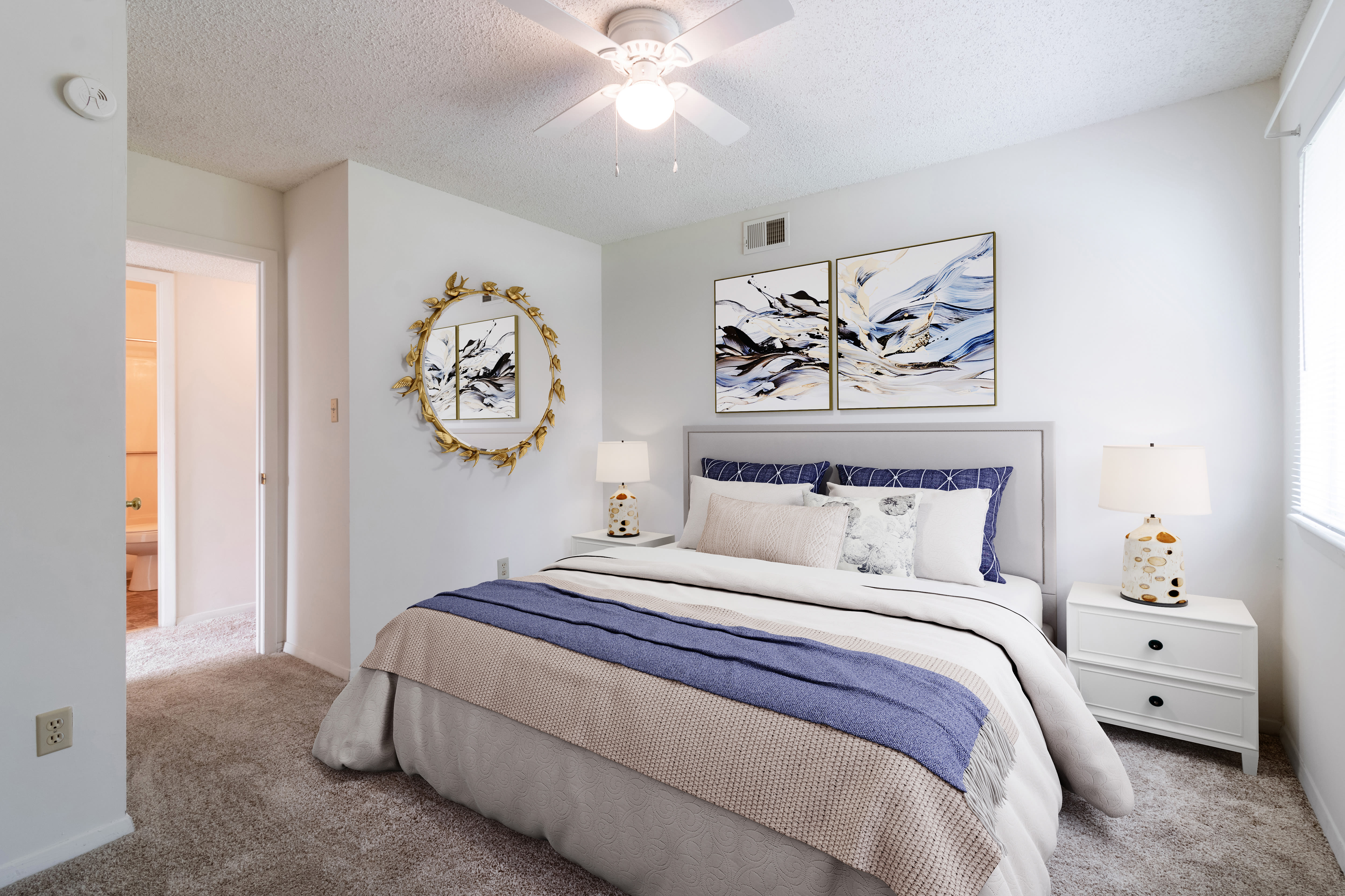 Well-lit bedroom with large comfortable bed, plush carpet, and ceiling fan at  Arbor Crest Apartments in Charlottesville, Virginia