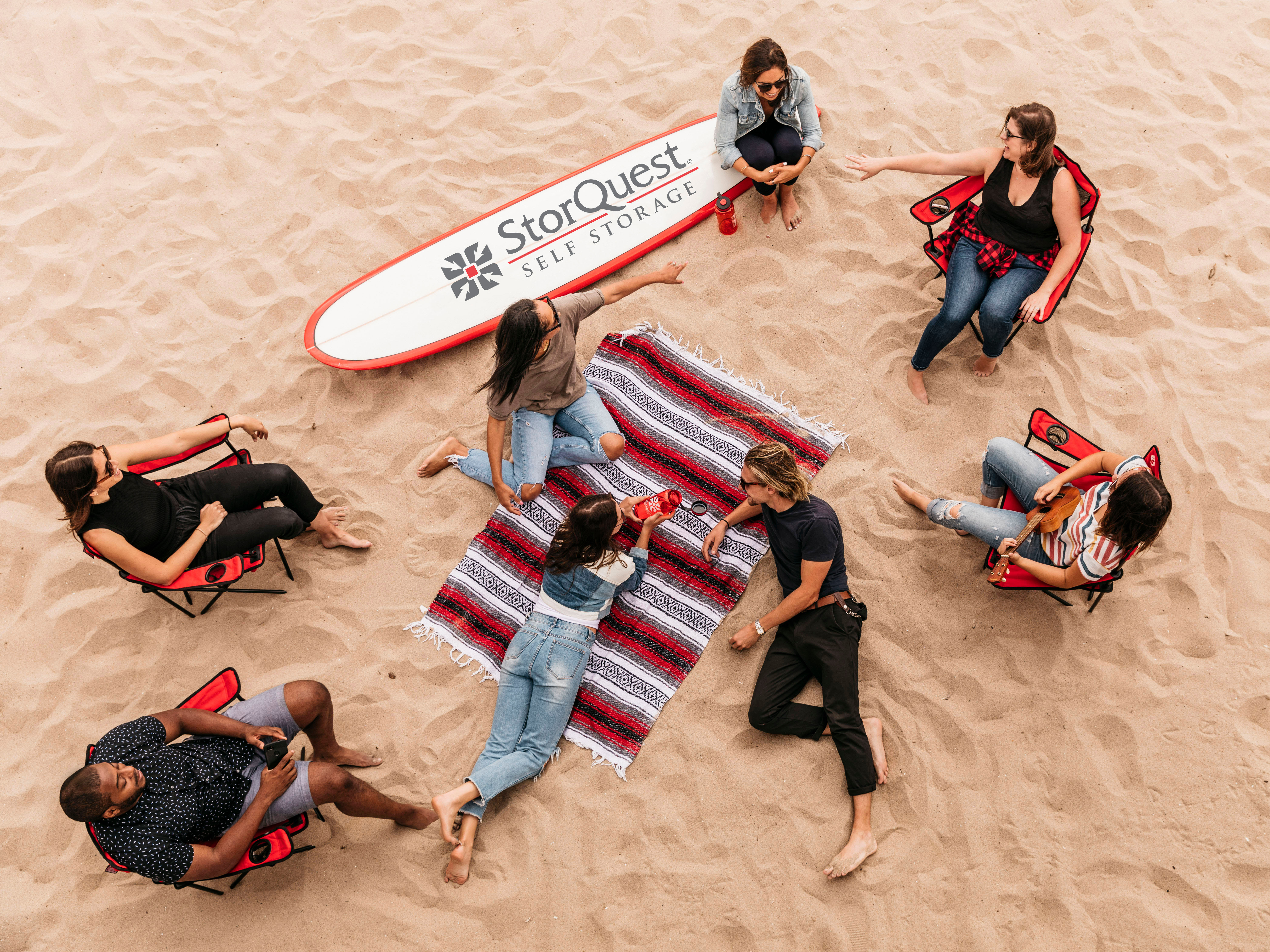 StorQuest employees at a beach event with surfboard. 