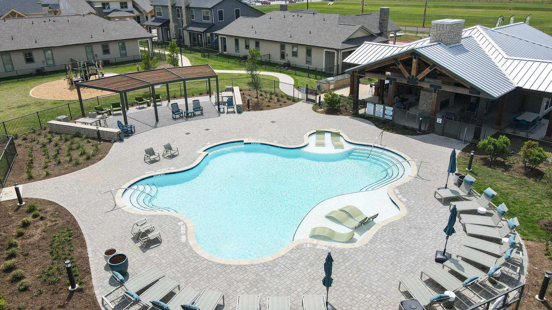 Aerial view of the resort-style swimming pool and clubhouse at Home At Waller in Waller, Texas