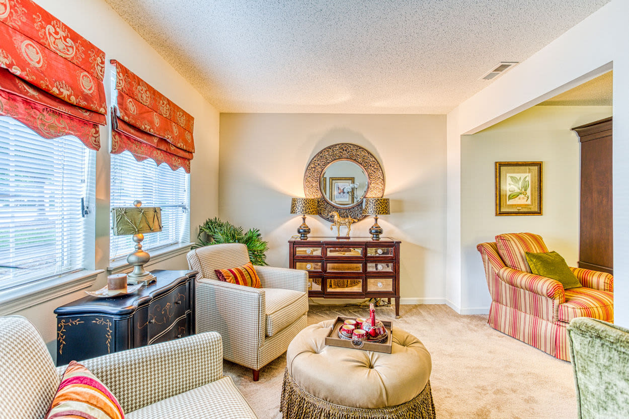 Well lit and open living room with plush carpeting and large windows at Brannigan Village in Winston Salem, North Carolina