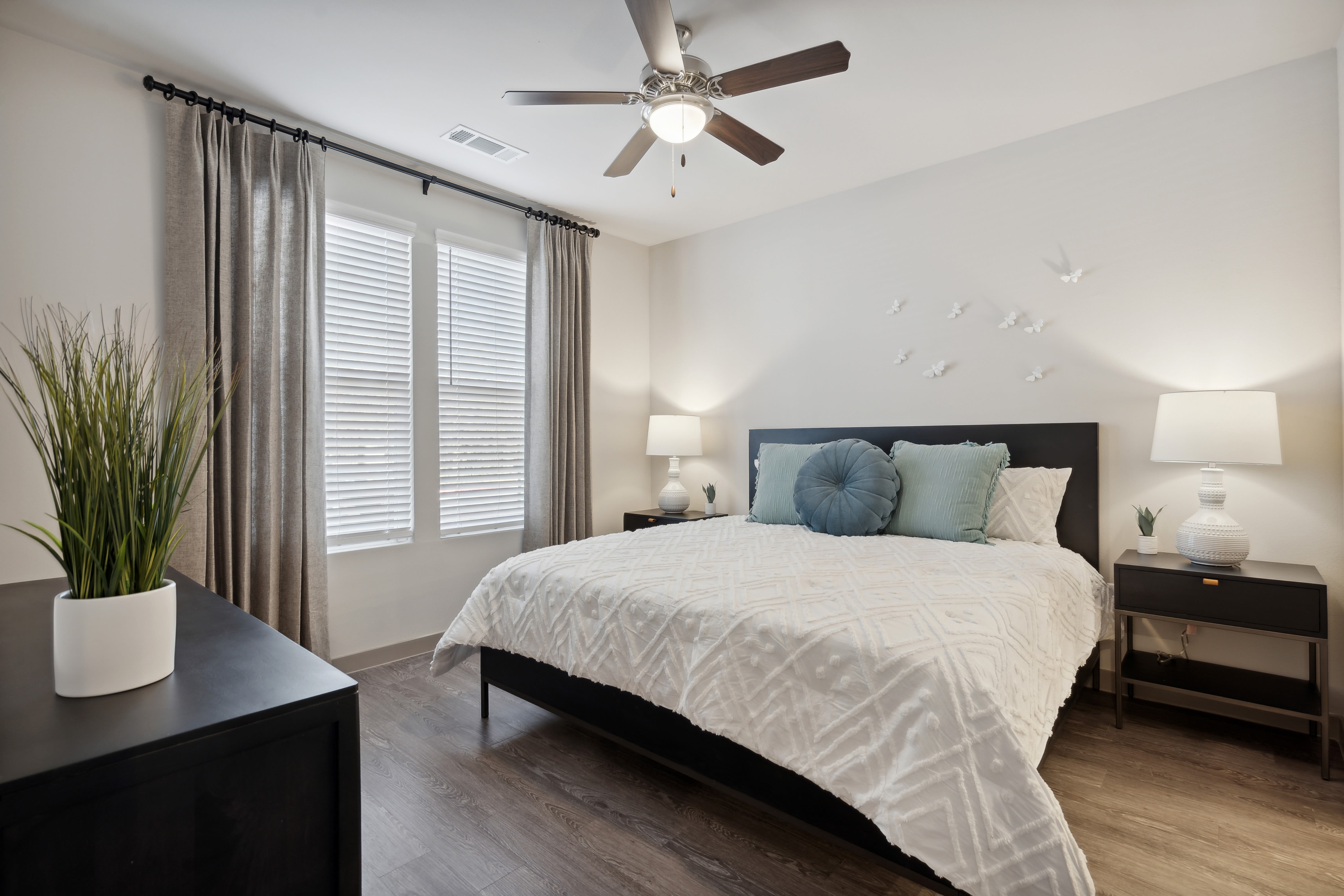 Spacious model bedroom with a ceiling fan and large windows at Radius Wolf Ranch in Georgetown, Texas 