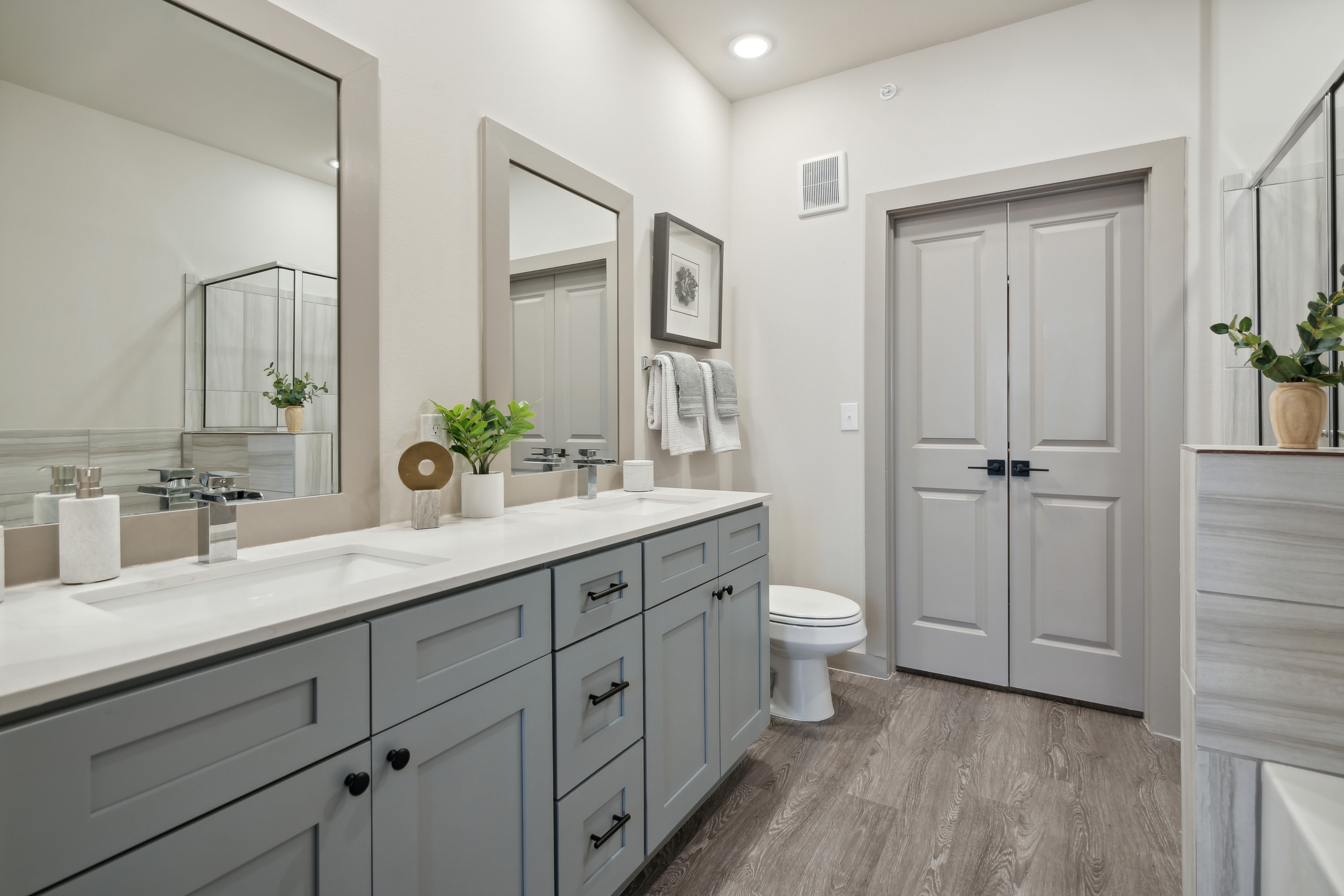 Model bathroom with dual vanity sinks and custom cabinetry at Radius Wolf Ranch in Georgetown, Texas
