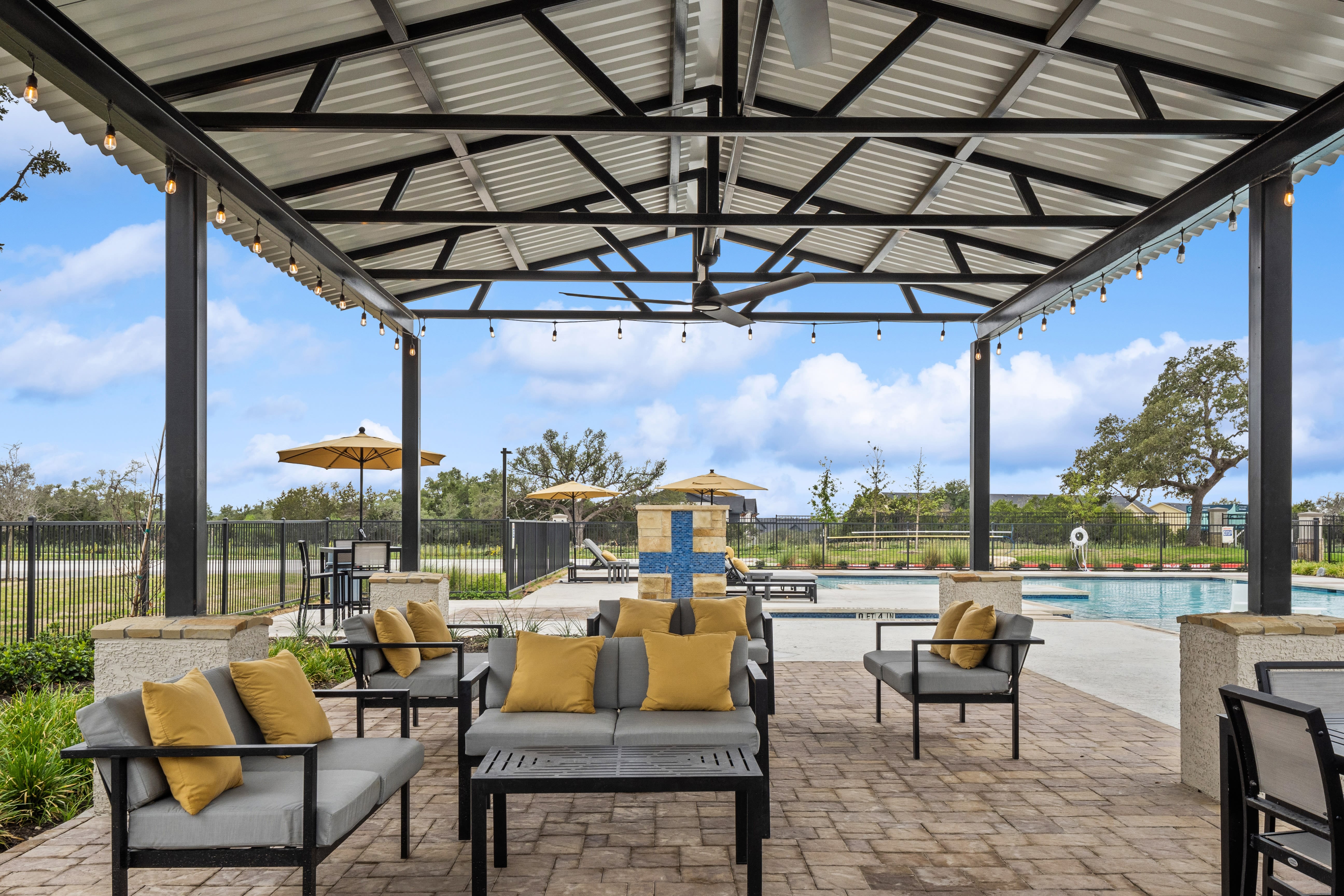 A covered lounge area near the swimming pool at Radius Wolf Ranch in Georgetown, Texas