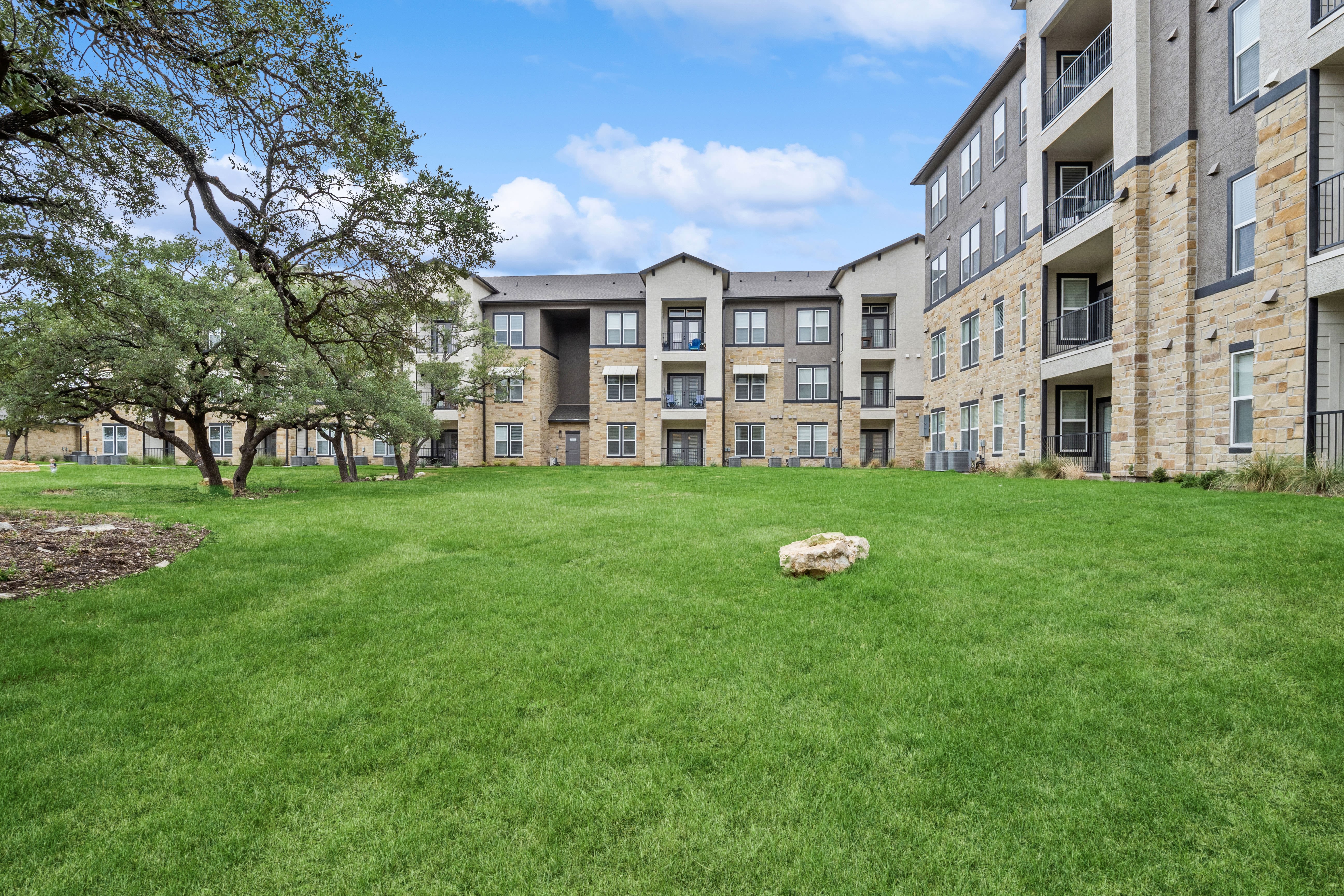 A well-manicured lawn with an apartment building in the background at Radius Wolf Ranch in Georgetown, Texas