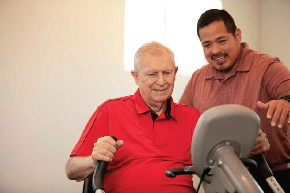 resident getting assistance with an excercise bike at Clearwater at The Heights in Houston, Texas