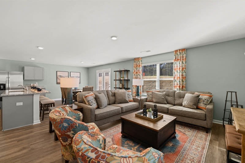 Living room with wood-style flooring and plush couch at The Lakes at Statham in Statham, Georgia