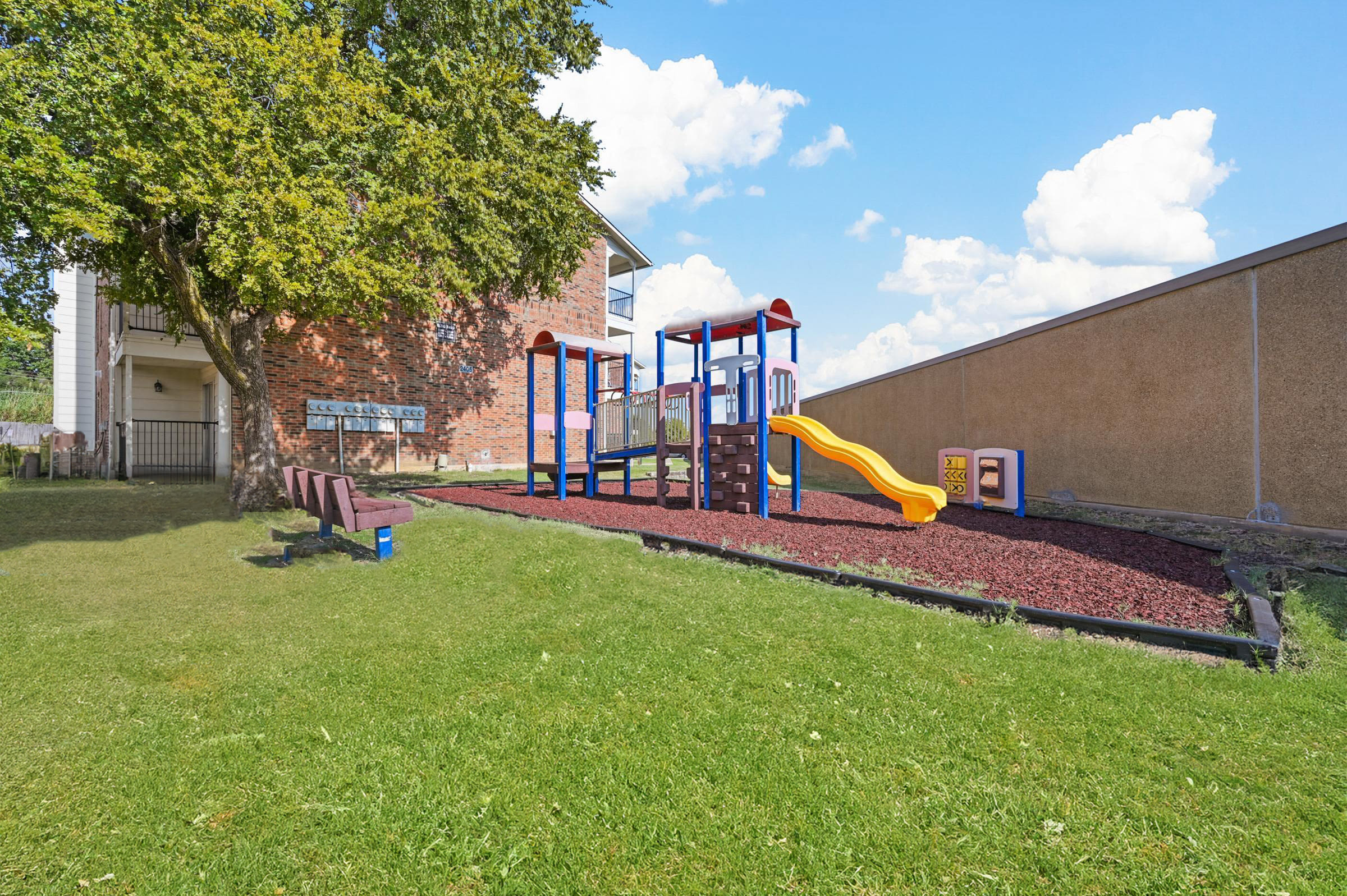 Children play area with a slide and a bench at Village Square in Irving 