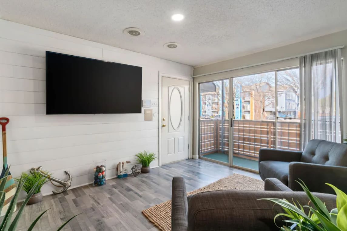 Community waiting room with a large TV and large windows at Junction at 7760 in Dallas, Texas