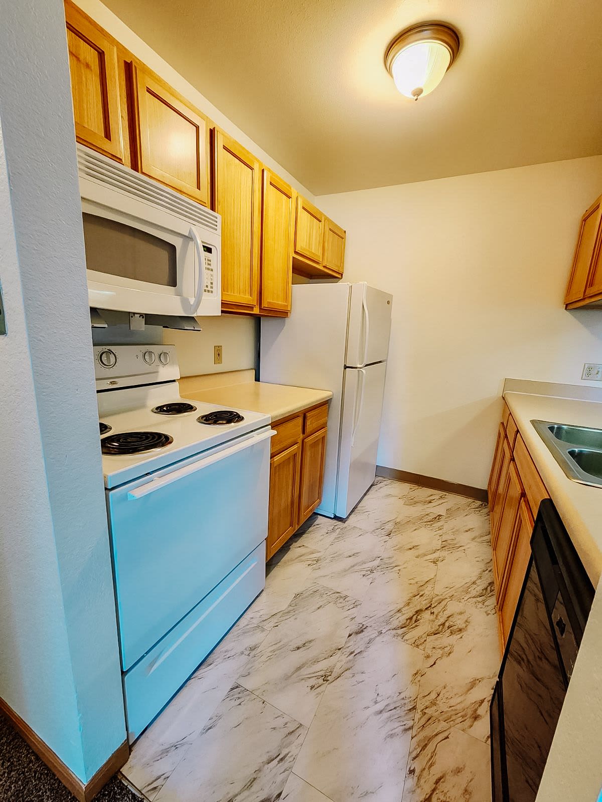 Kitchen with refrigerator and wooden cabinets at Rivercrest Apartments in Croswell, Michigan