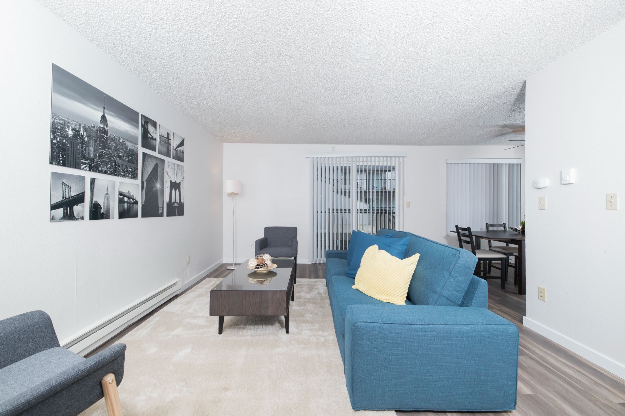 Spacious living room with couch, chairs, and hard-wood style flooring at Solana Apartments in Burien, Washington