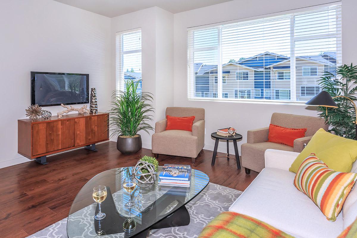 Thoughtfully designed living room with wood flooring and plenty of natural light at The Woodlands Townhome Apartments in Snoqualmie, WA