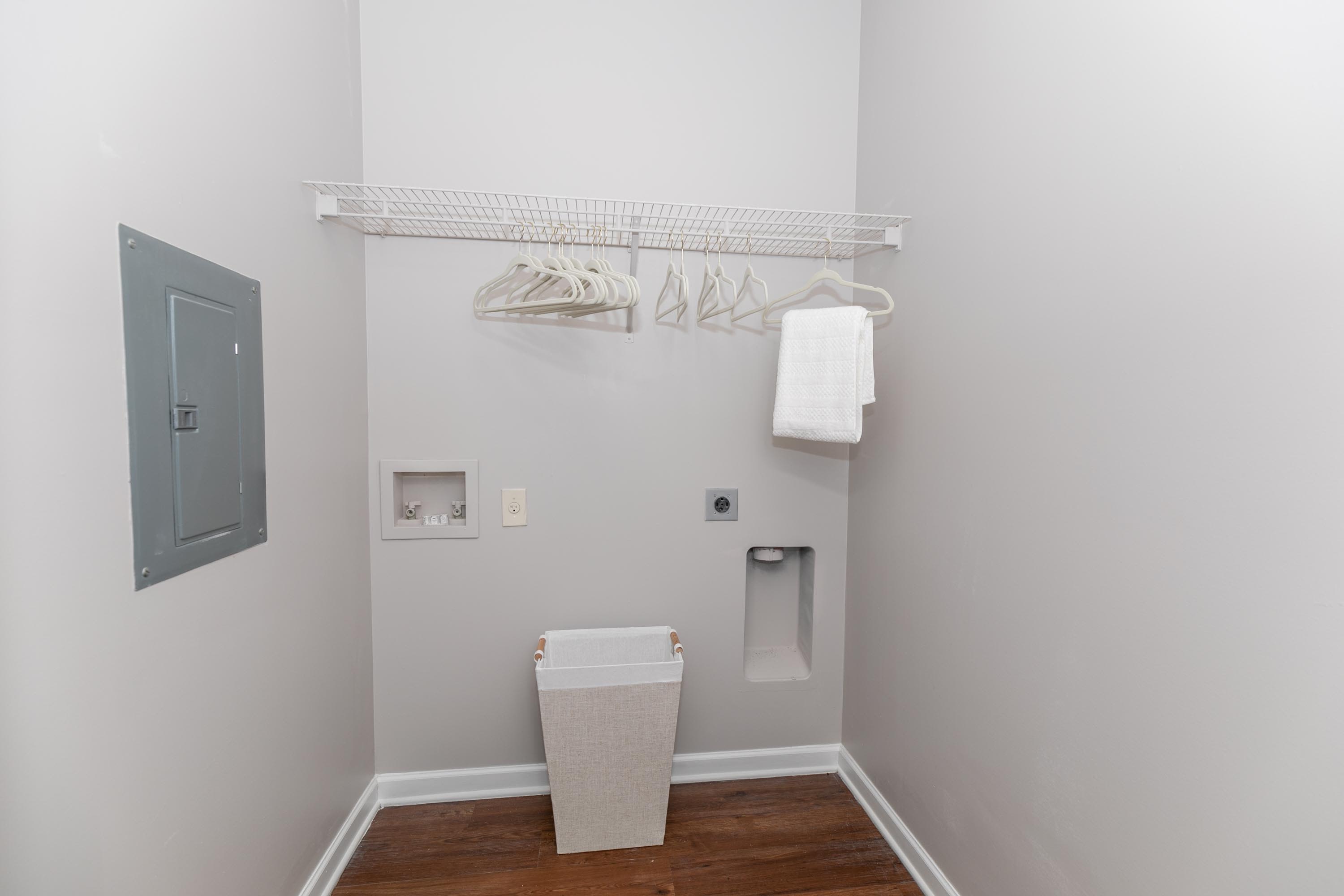 A small closet space containing a toilet and garments hanging on the wall at Thomaston Crossing in Macon, Georgia