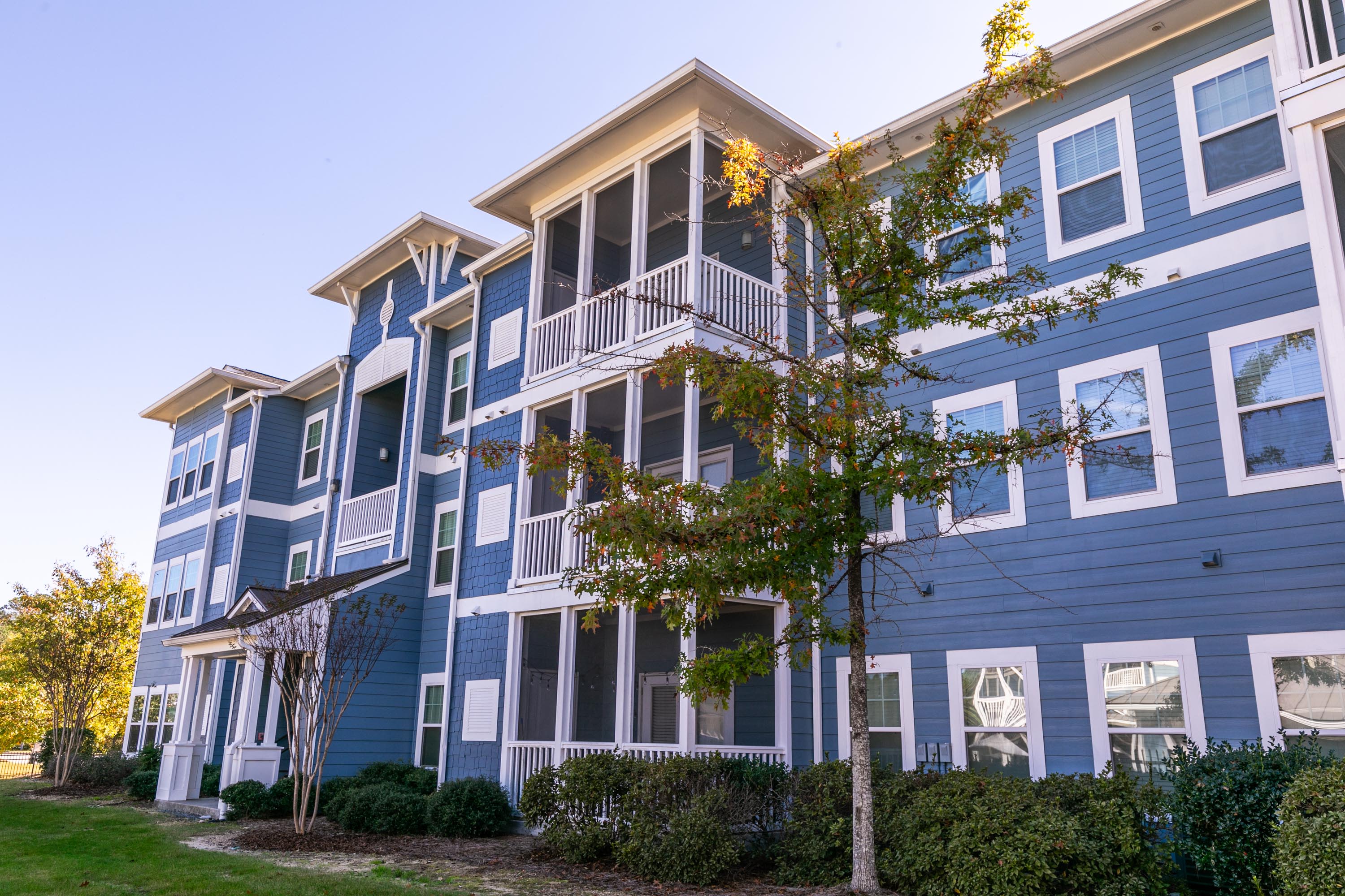 A modern blue apartment building with white trim and blue siding at Thomaston Crossing in Macon, Georgia