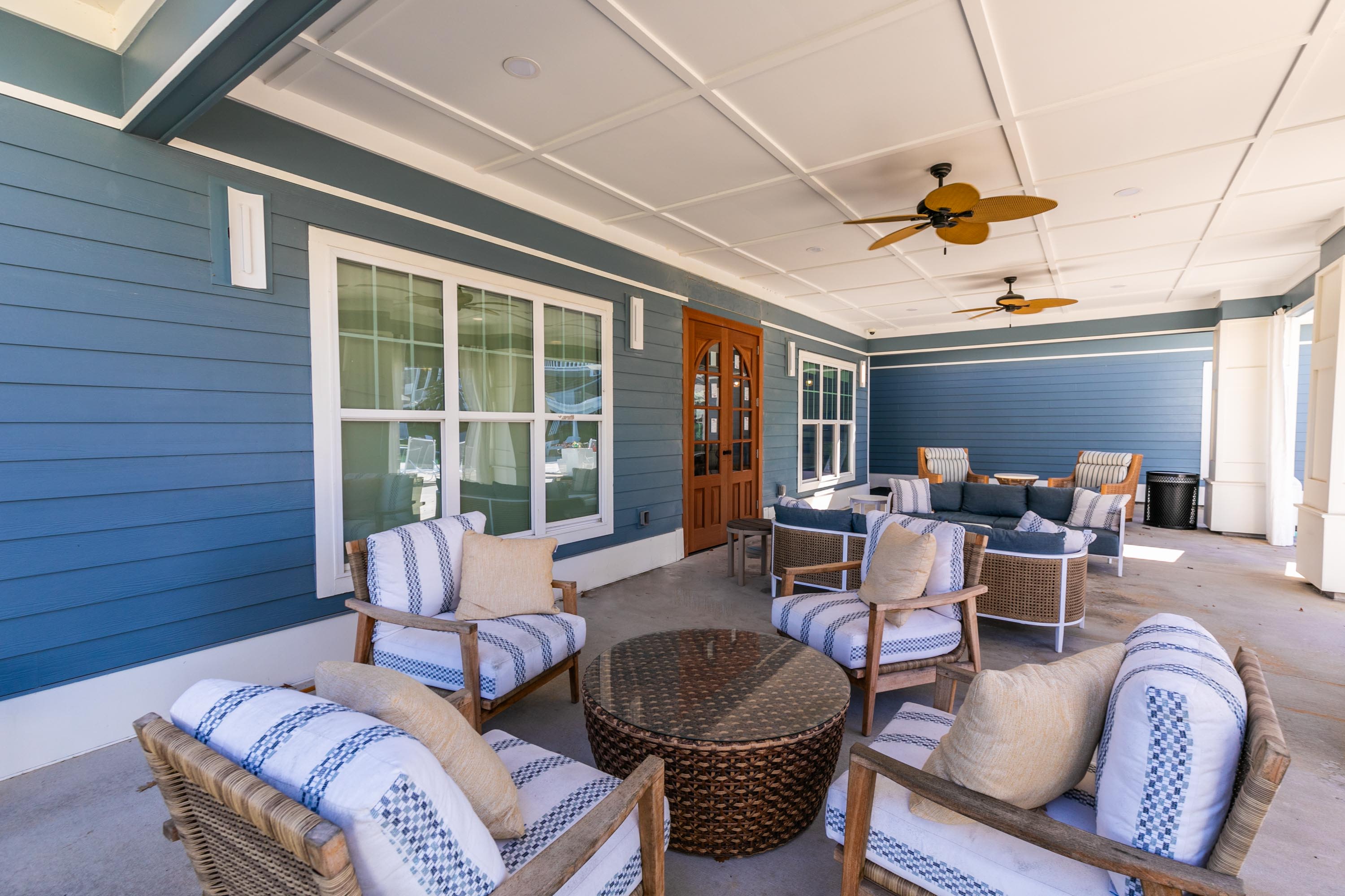 A stylish covered porch showcasing wicker furniture and a ceiling fan at Thomaston Crossing in Macon, Georgia